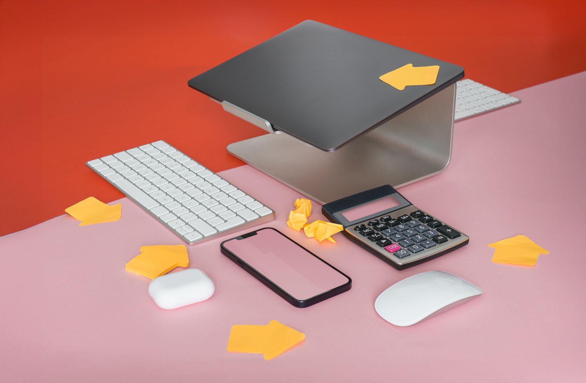 Stylish workspace setup with laptop, keyboard, and calculator on colorful background.