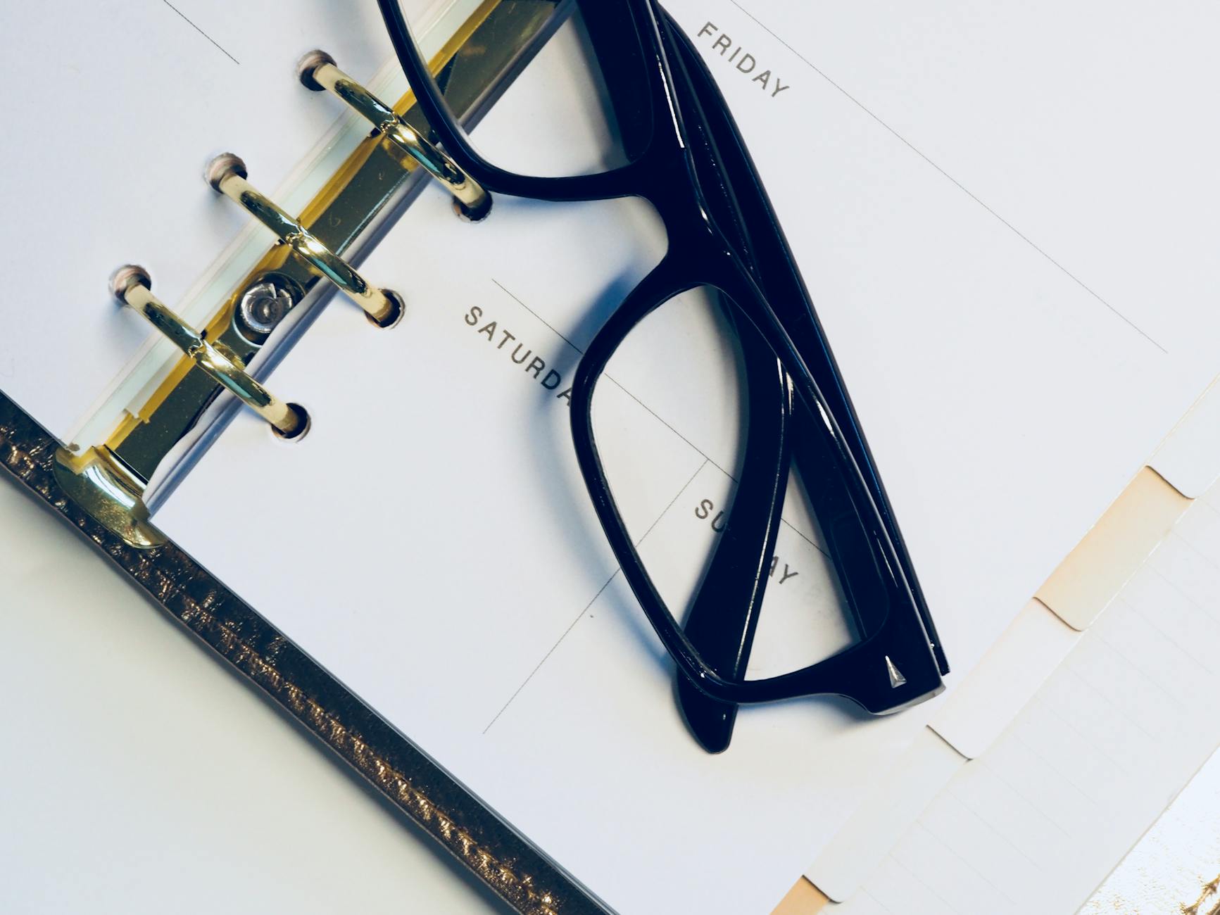 Detailed shot of a person's hand writing notes on a calendar using a blue marker.
