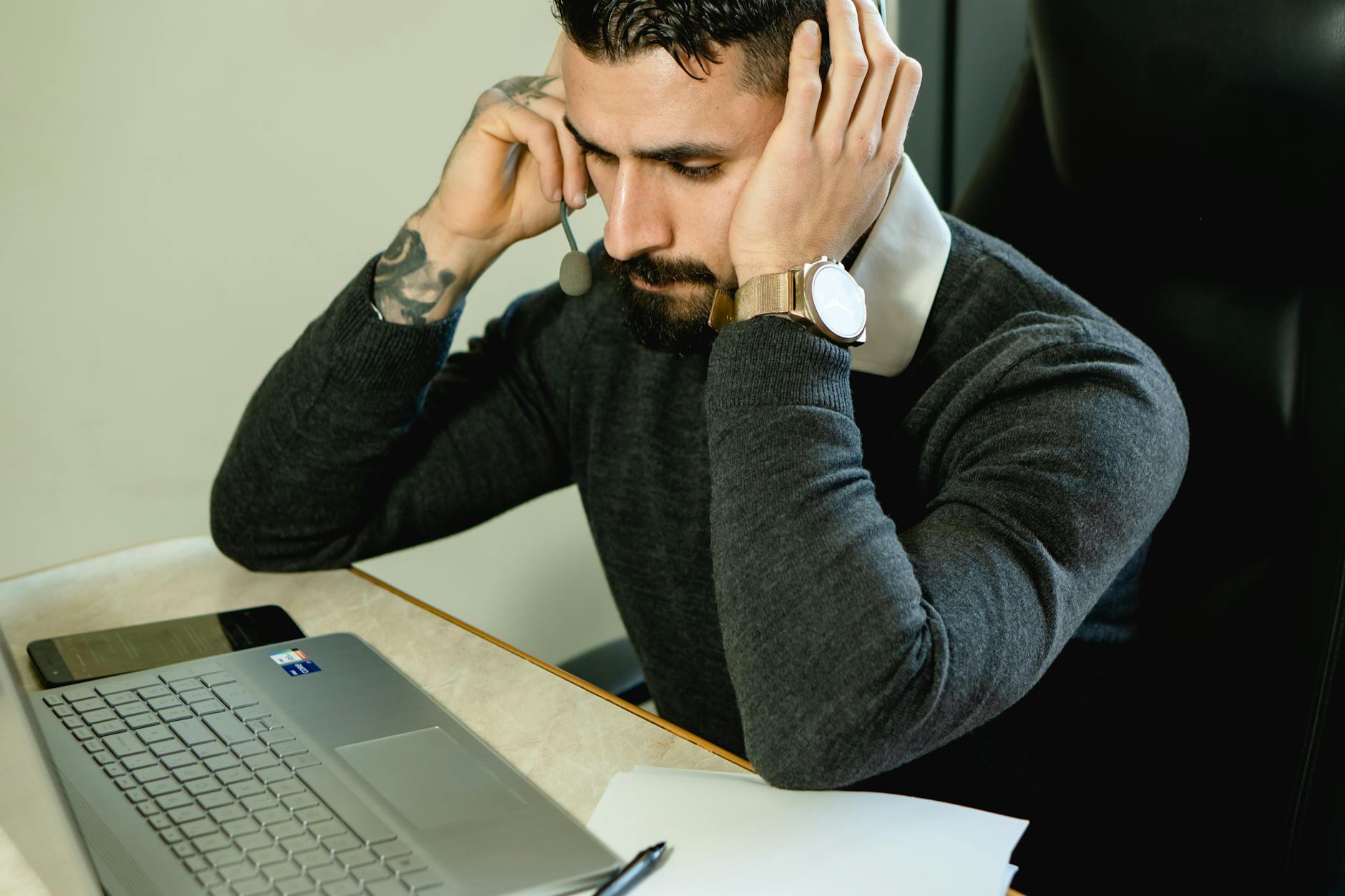 Bearded man in a call center focused on providing customer support using a laptop.