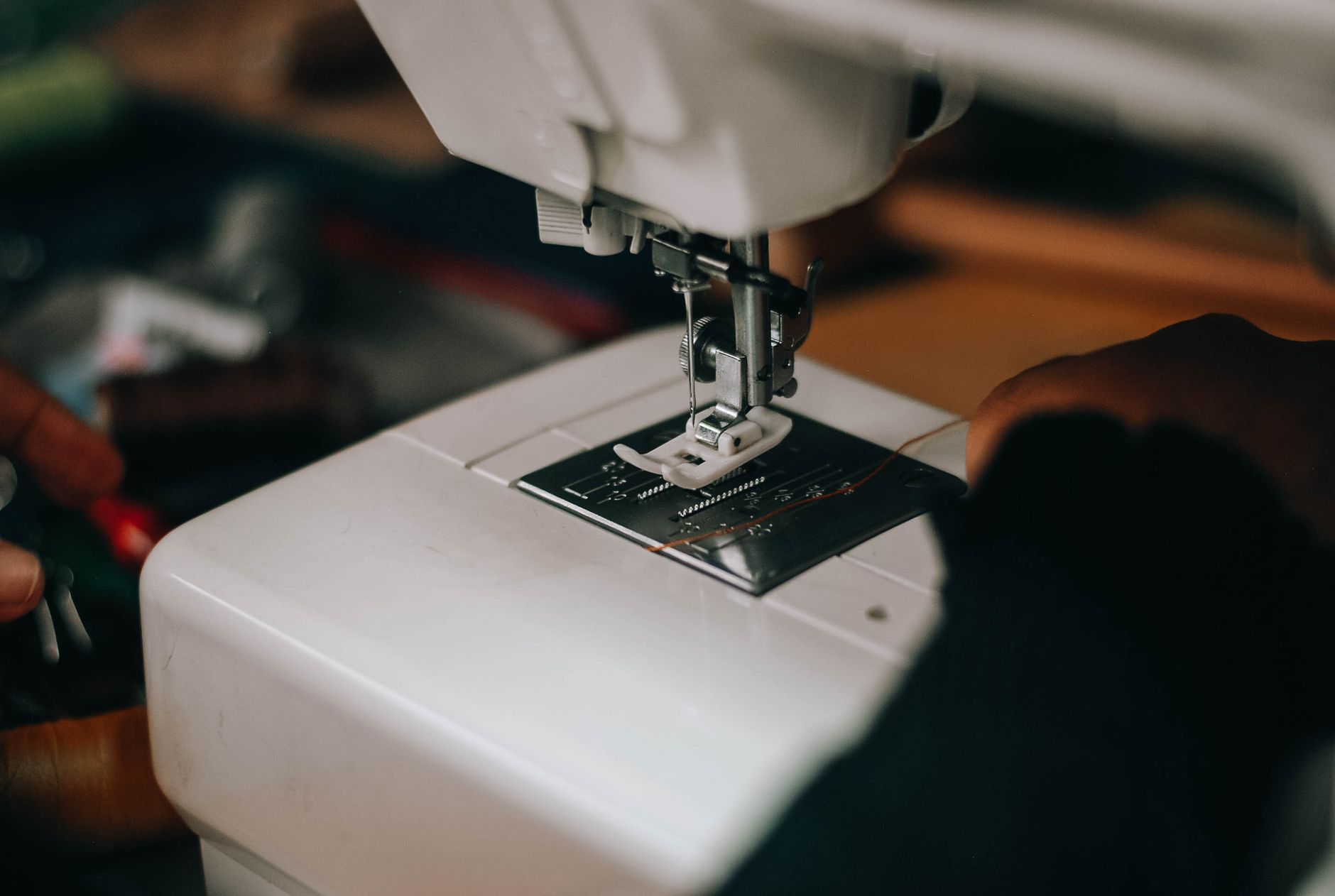 Detailed close-up of hands using a sewing machine, focusing on the needle and fabric.