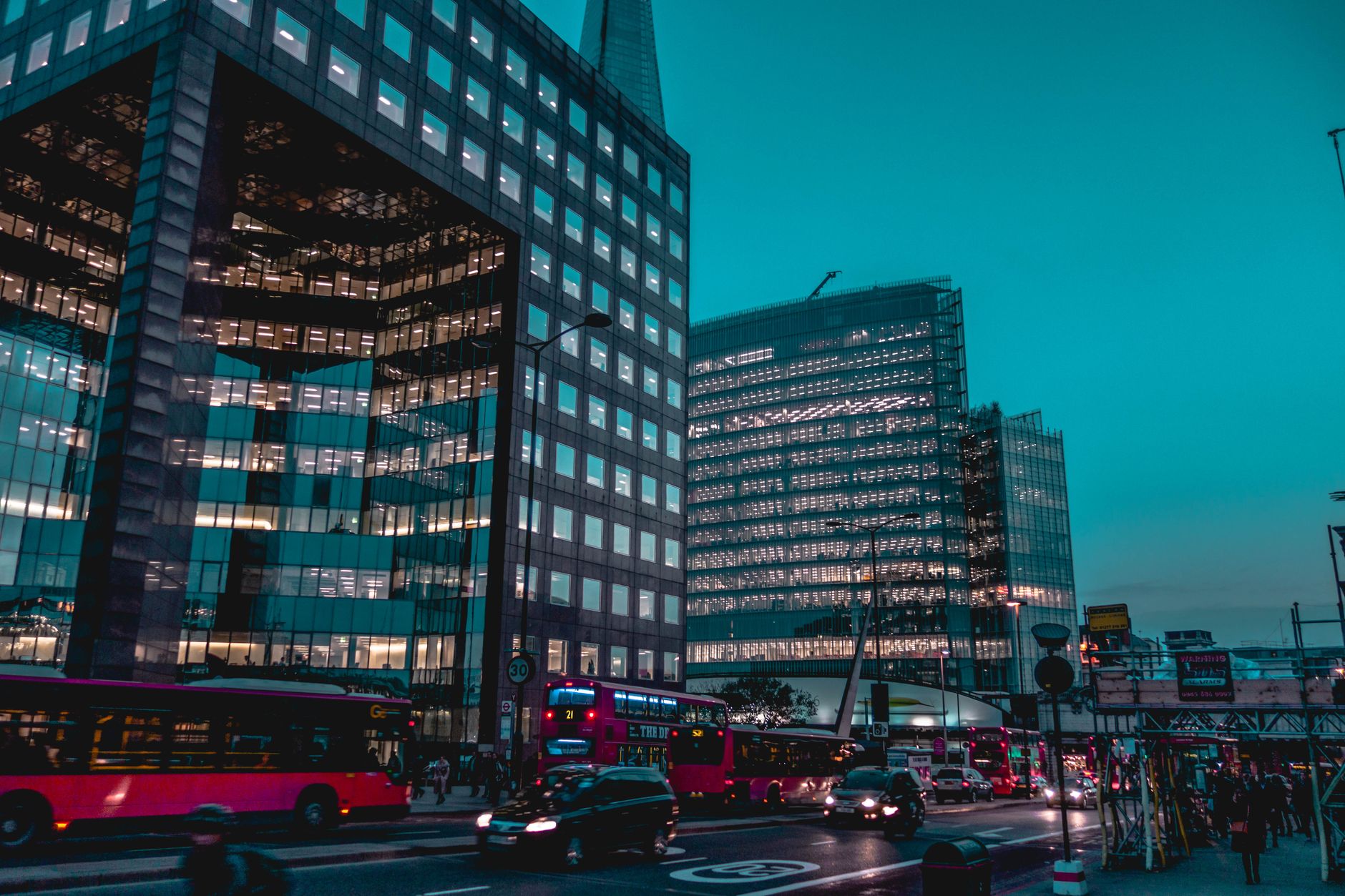 A bustling city street with modern buildings and urban traffic just after sunset, showcasing architectural grandeur.
