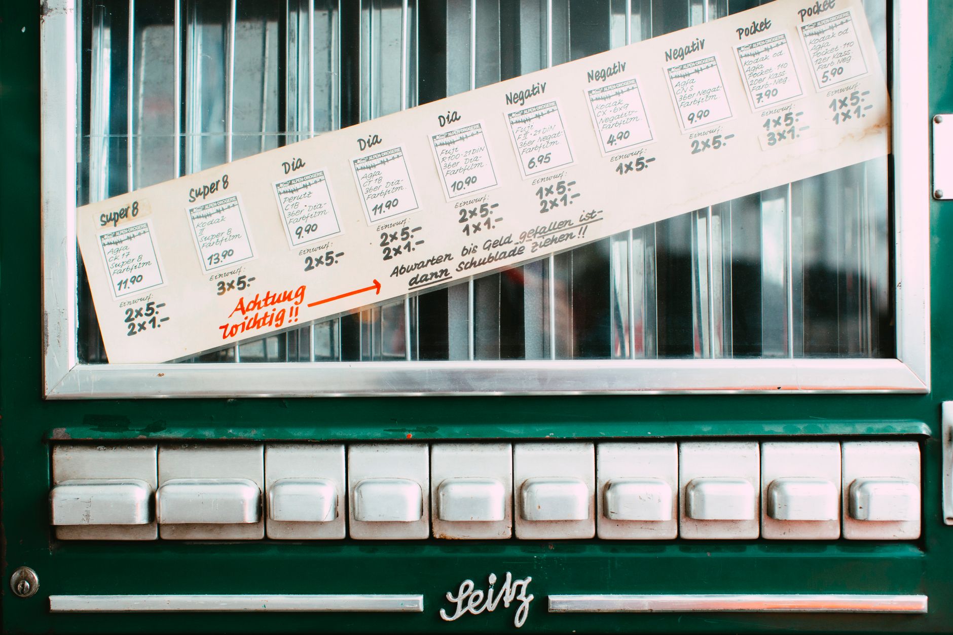 Vintage vending machine featuring German instructions and multiple white buttons.