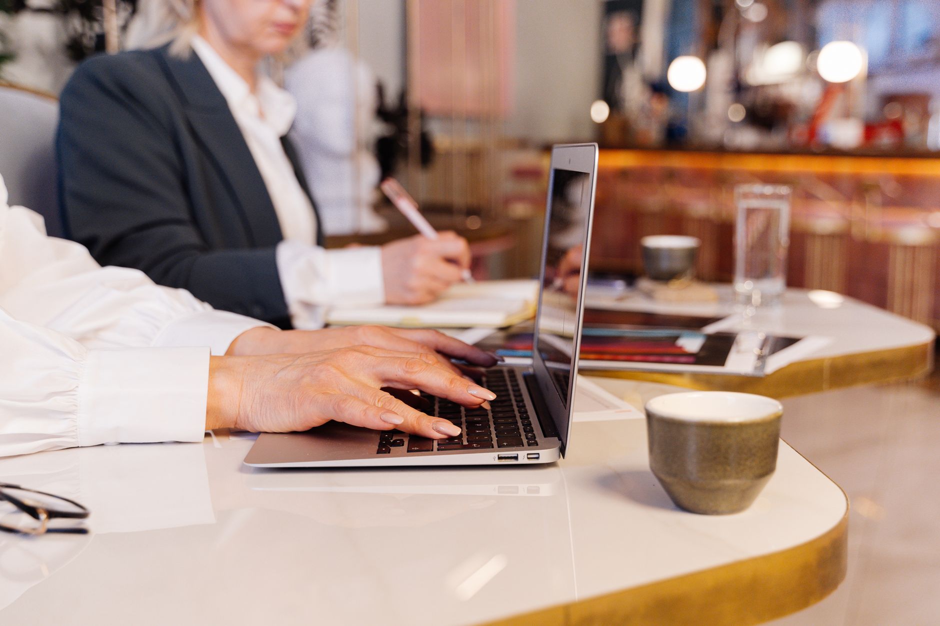 Close-up of business professionals using a laptop in a modern office setting.