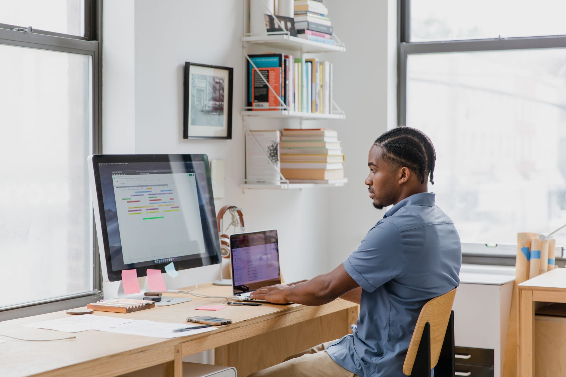 Focused man at home office desk working on dual screens. Ideal for remote work themes.