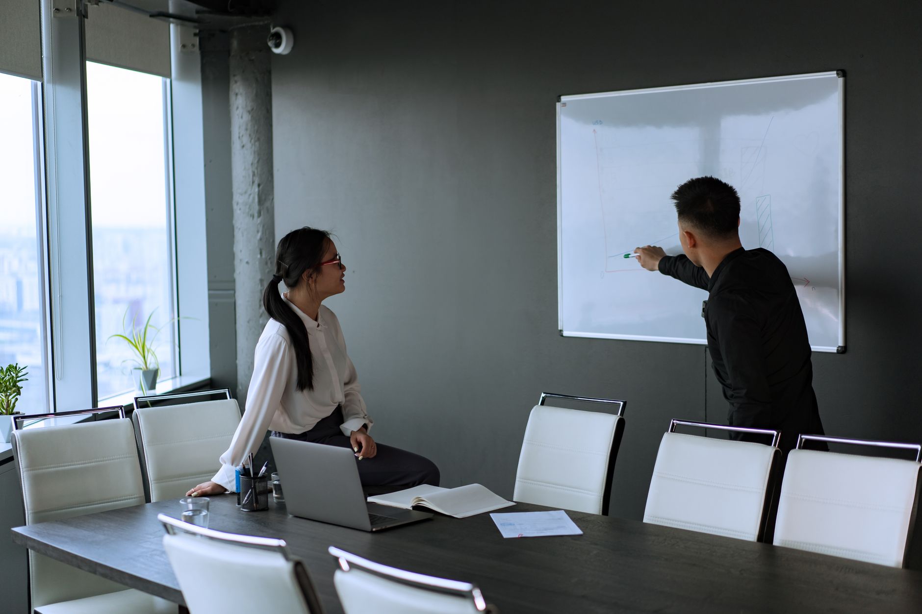 Colleagues engage in a productive office meeting with a whiteboard presentation.