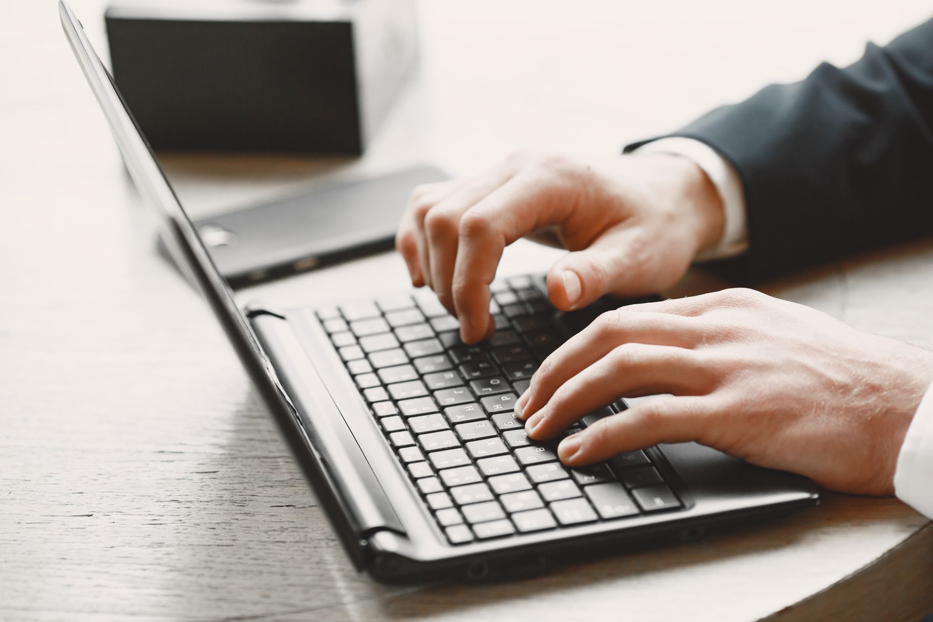 Close-up of hands typing on a laptop in a professional setting. Ideal stock photo for business and technology themes.