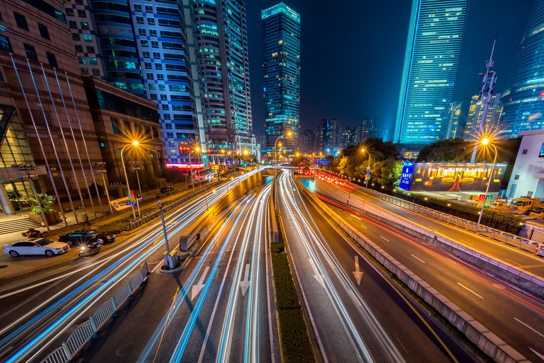 Dynamic long exposure night shot of urban cityscape with vibrant light trails and towering skyscrapers.