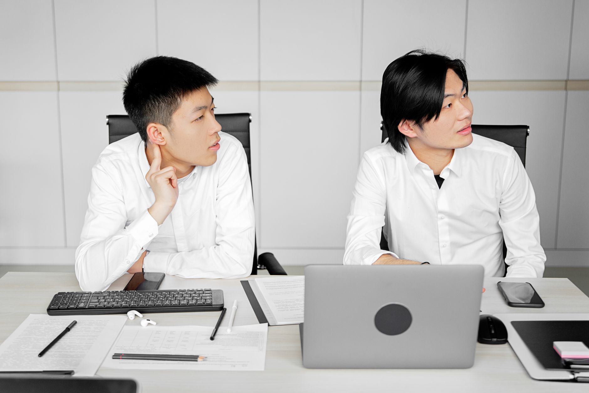Two professionals in a modern office engaged in a business meeting at a desk.