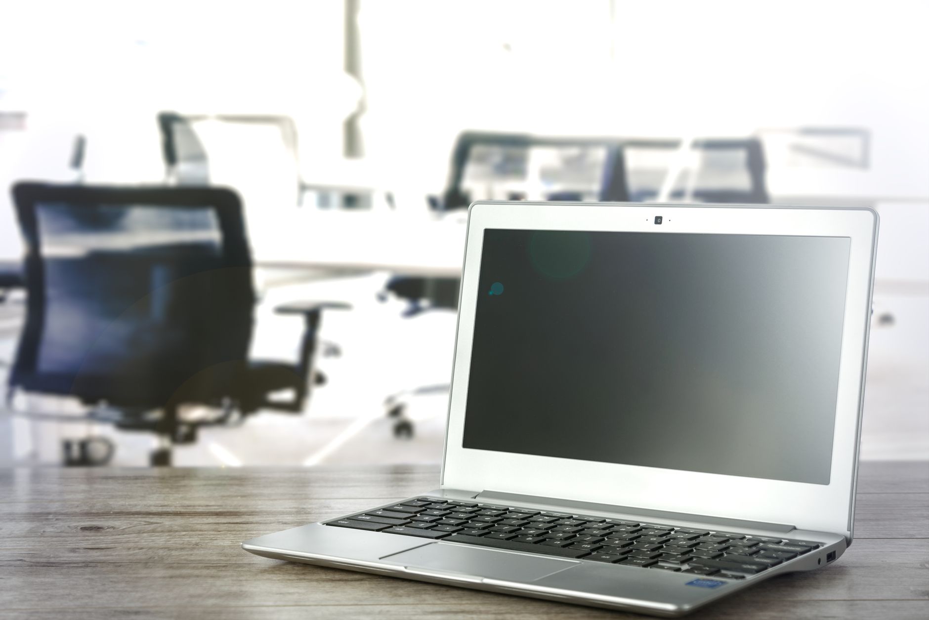 A sleek laptop on a desk in a bright and modern office setting.