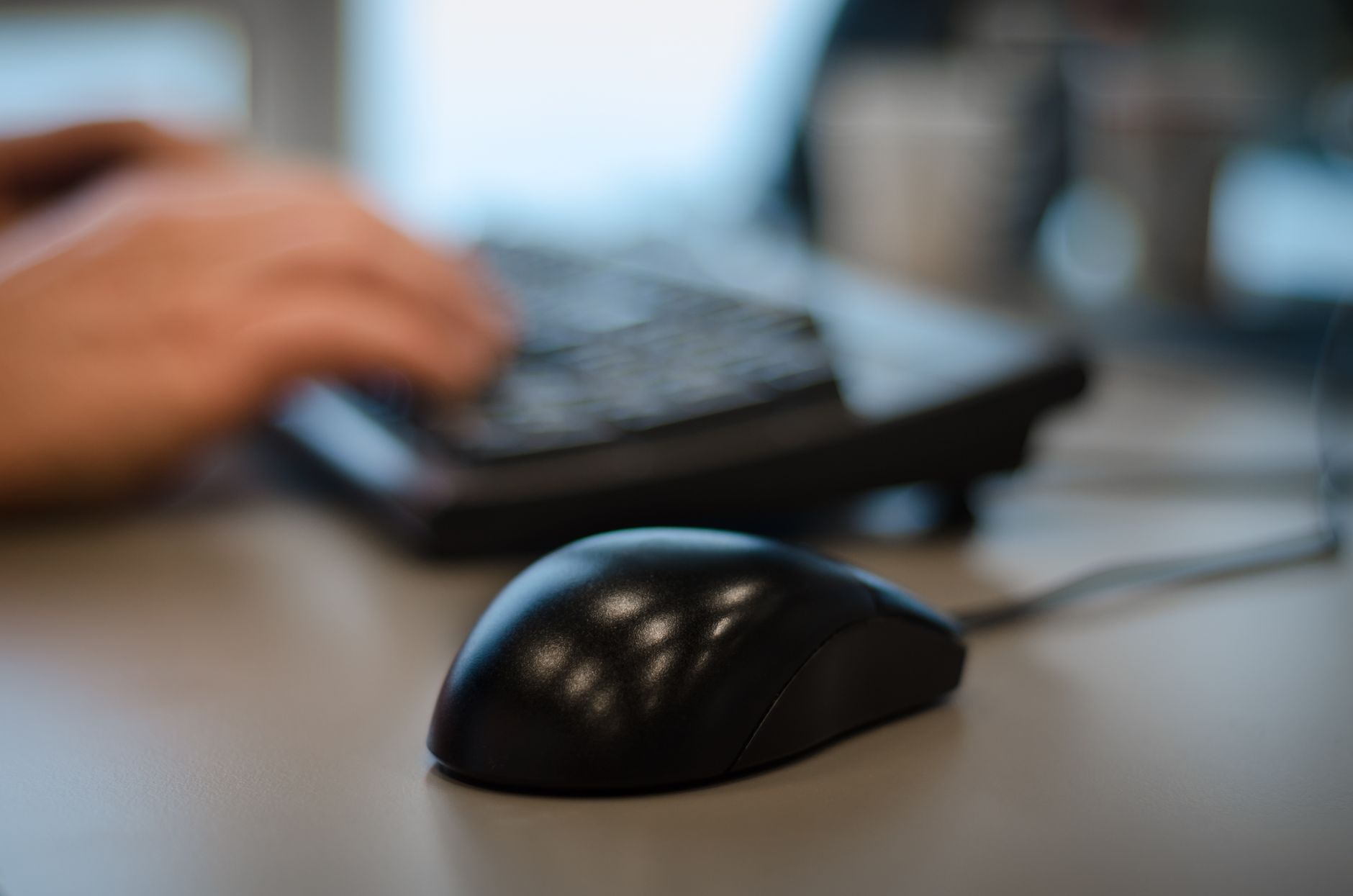 Blurry background with a focus on a computer mouse in an office setting.