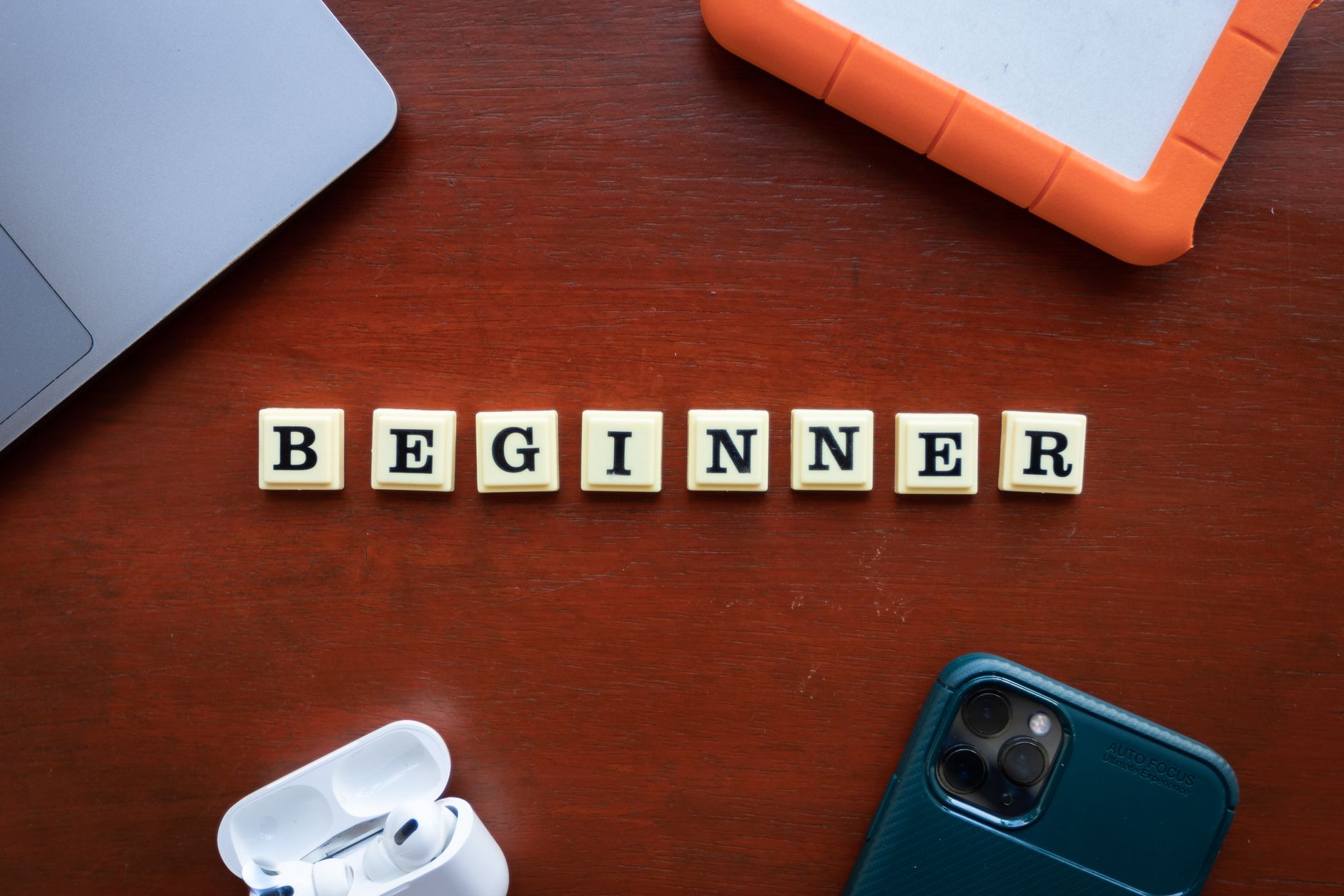 A top view of beginner workspace items including gadgets and letter dice on a wooden desk.