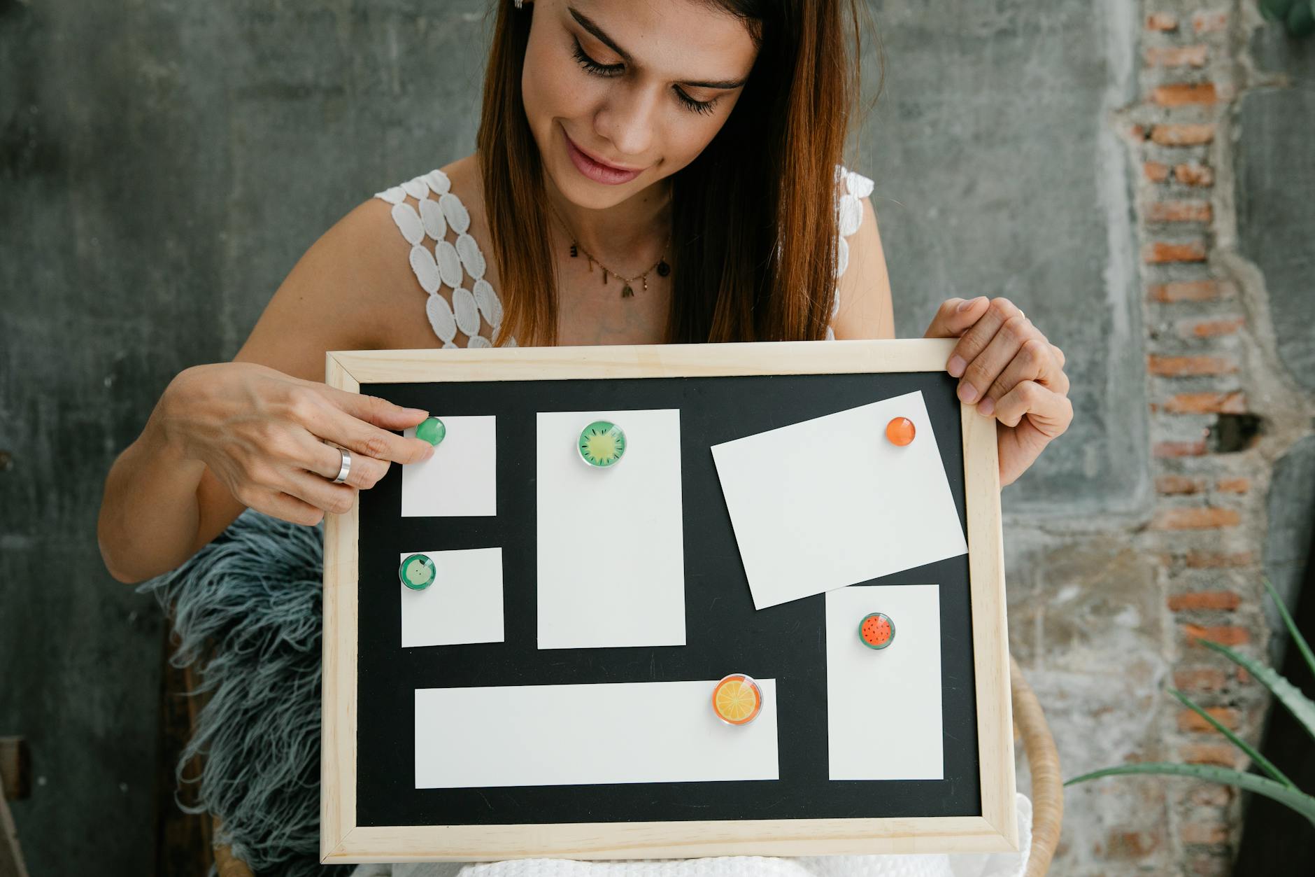 Woman arranging magnets on a blank magnetic board, smiling indoors.
