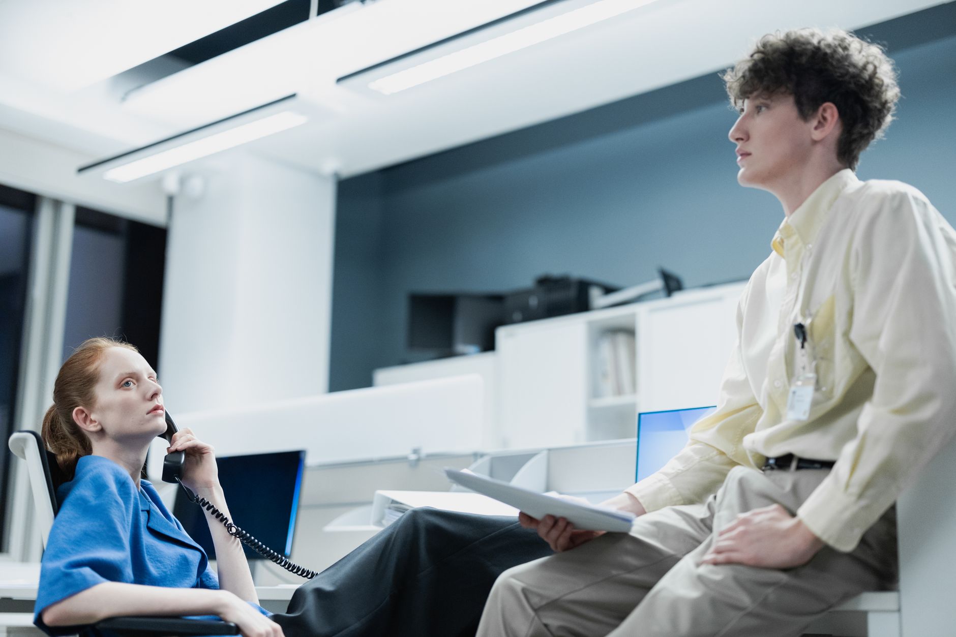 Two office workers engage in conversation, creating a professional work ambiance.