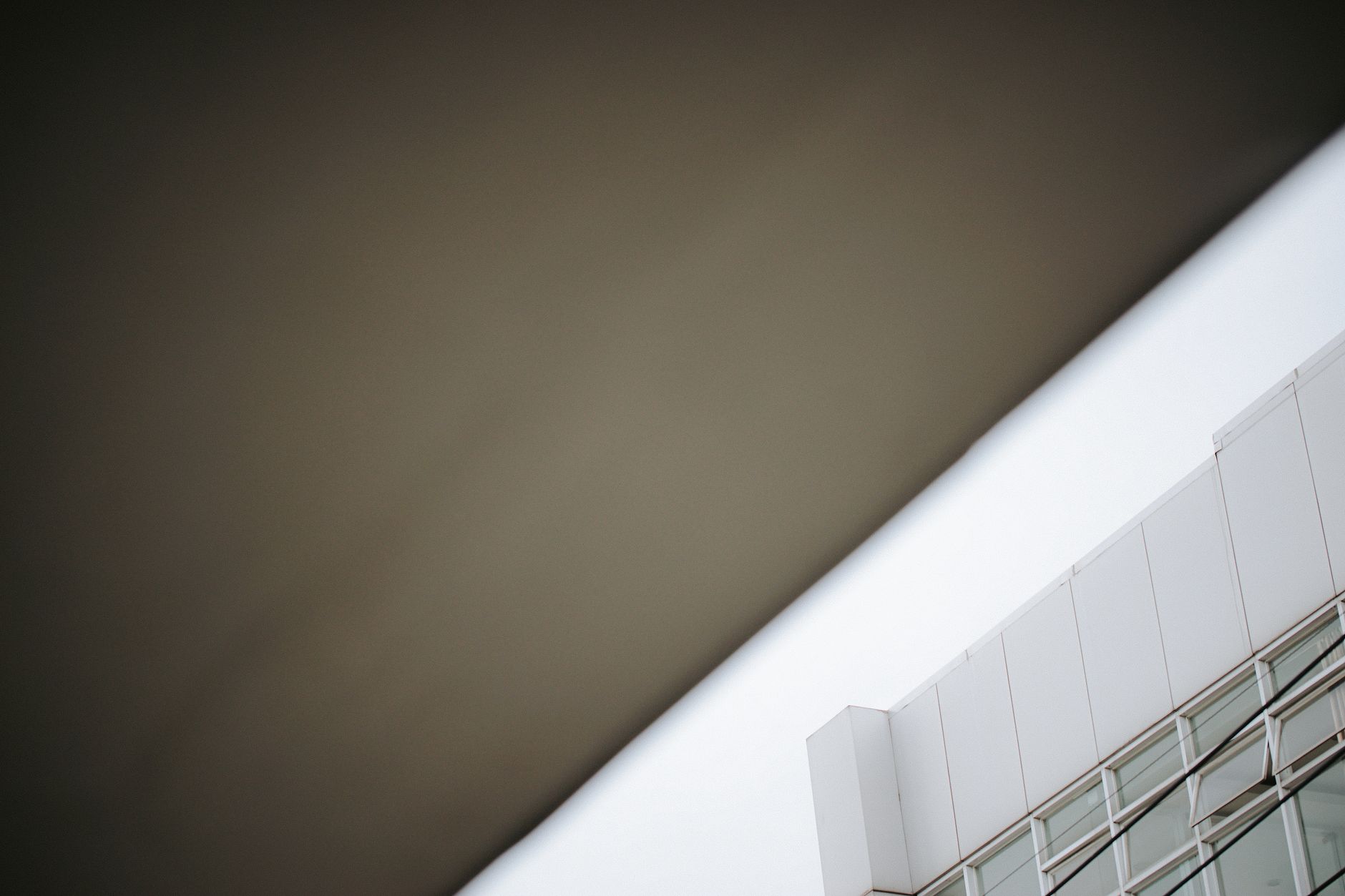 Low-angle view of a modern building with a glass facade and geometric structure.
