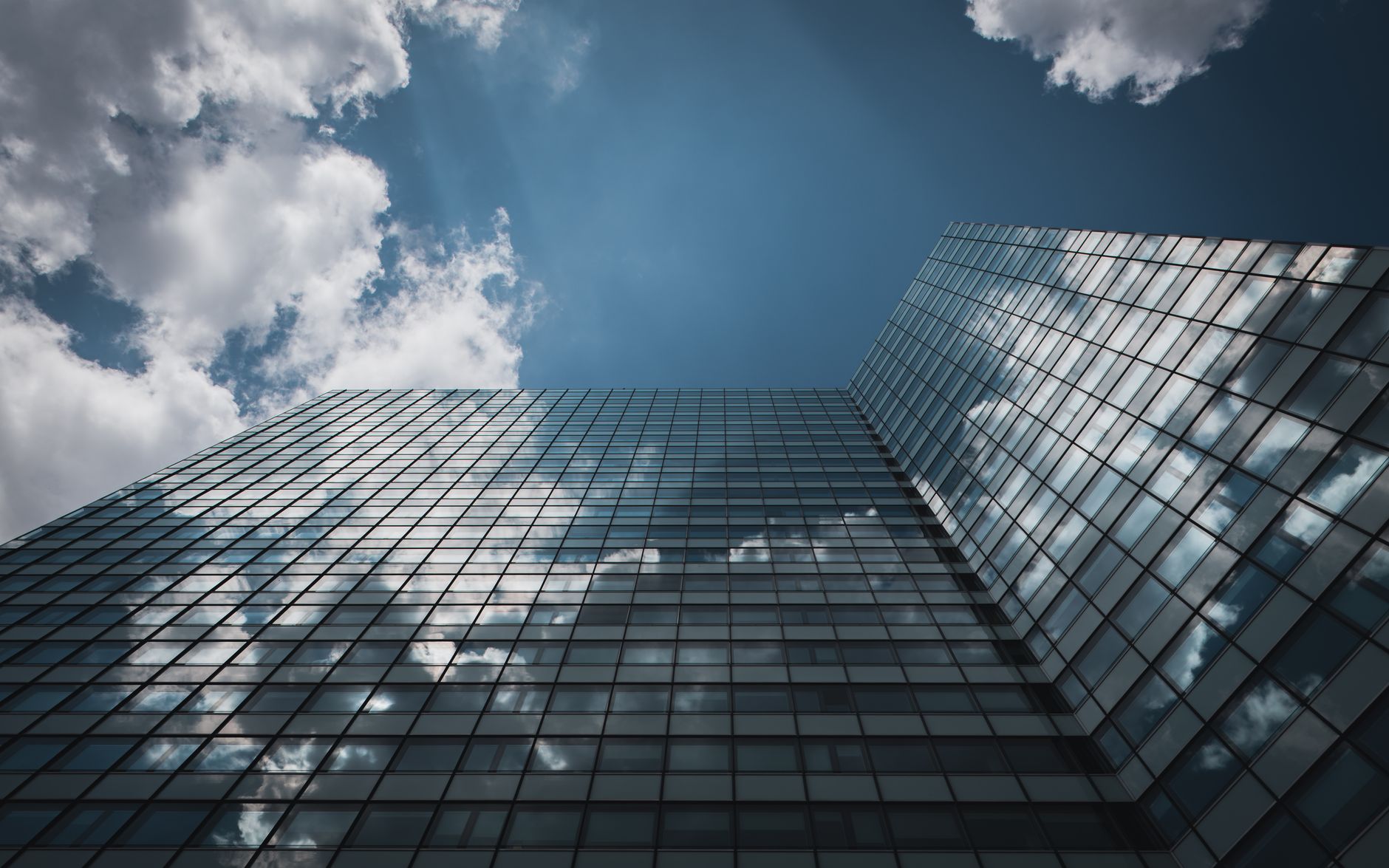 Low angle view of a glass skyscraper in Hamburg reflecting clouds in a clear sky.