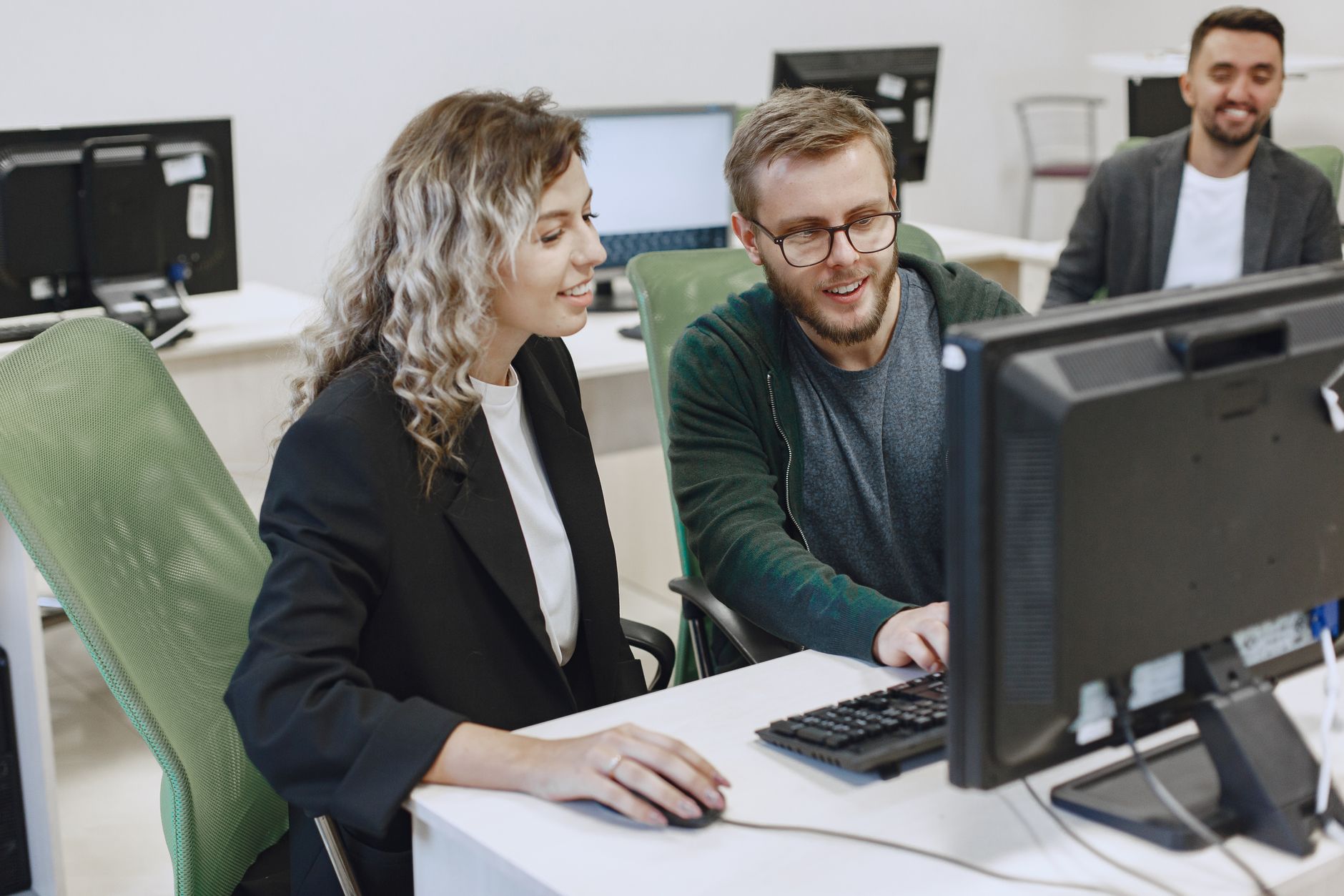 Two colleagues collaborating on a computer in a modern office environment.