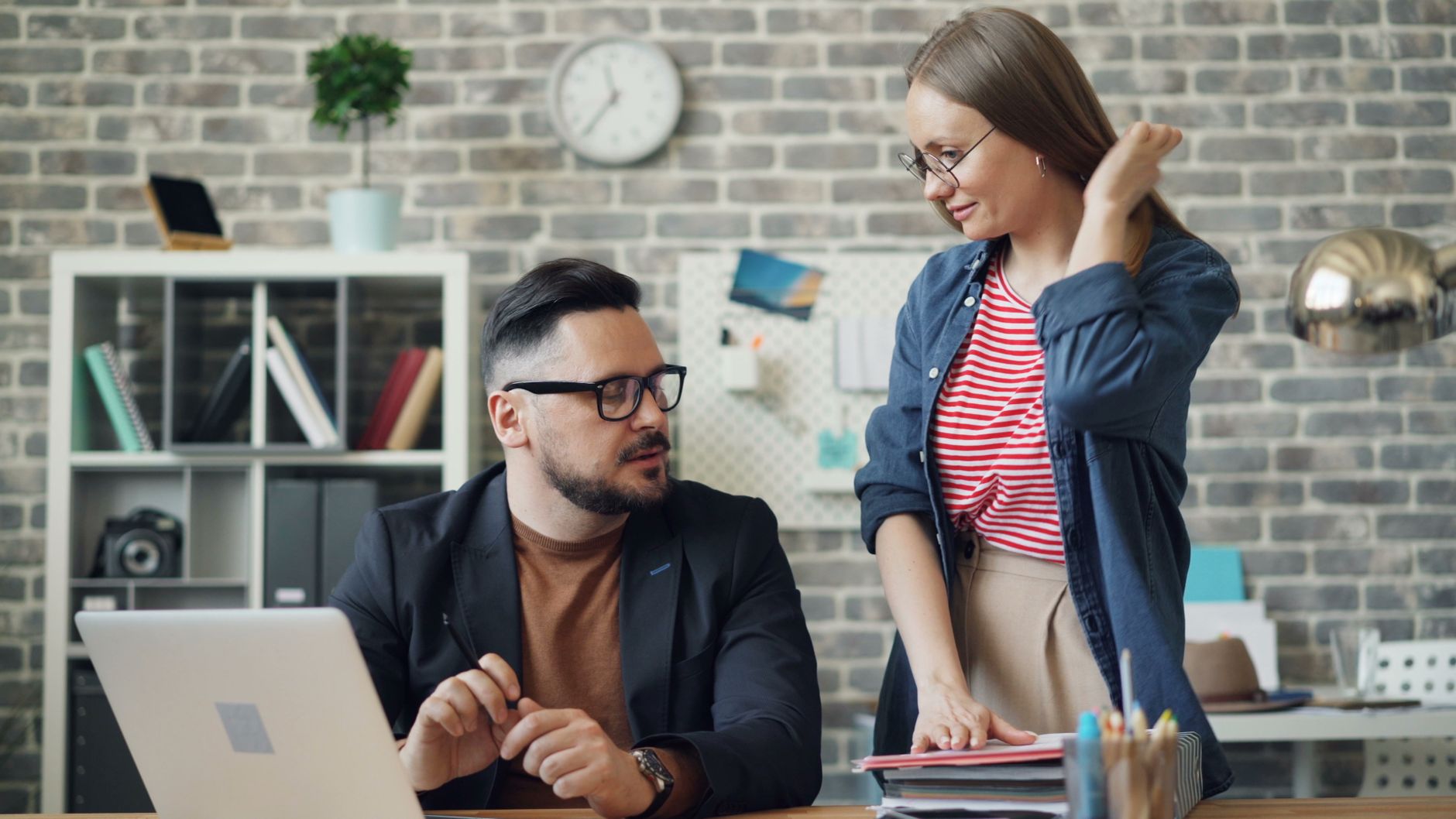 Business professionals discussing work at a desk in a contemporary office setting.