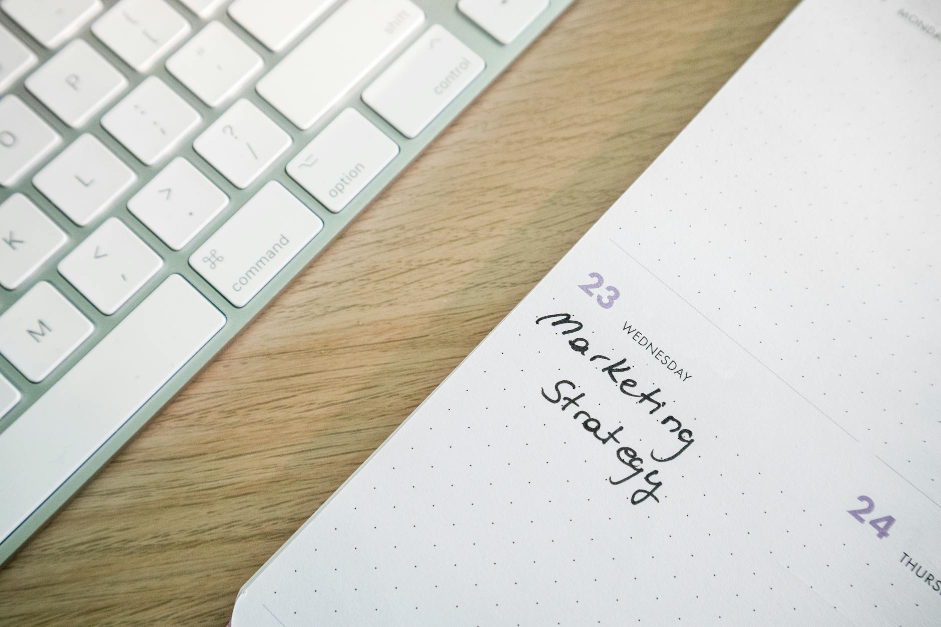 Detailed shot of a person's hand writing notes on a calendar using a blue marker.