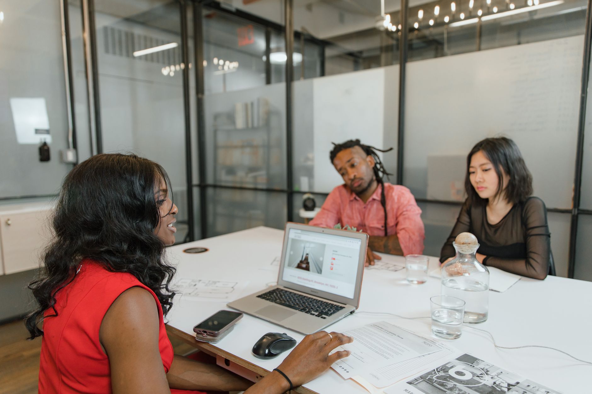 A diverse team collaborates in a modern office setting, discussing over laptops and documents.
