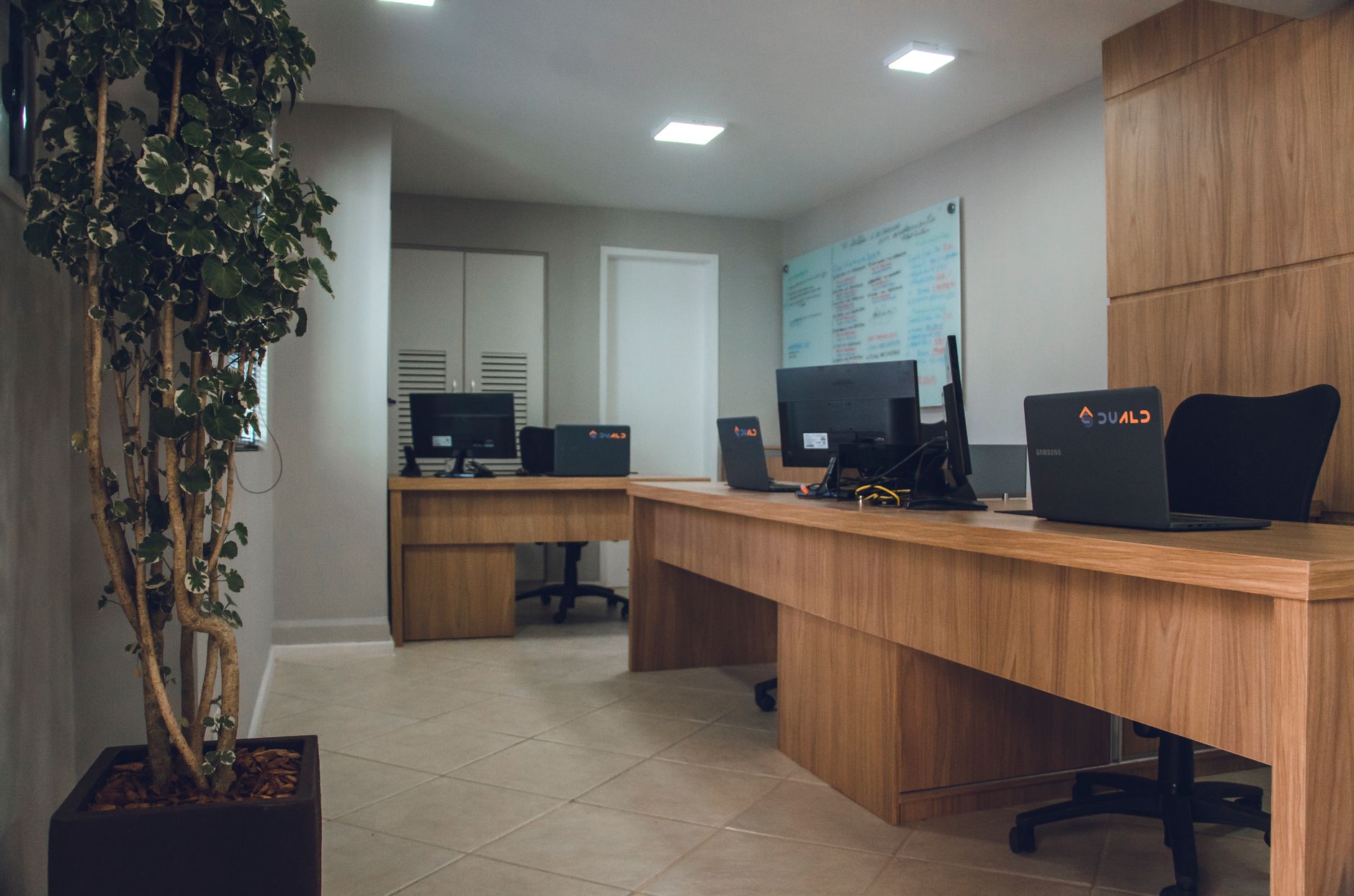 Contemporary office space featuring desks with computers and revolving chairs.