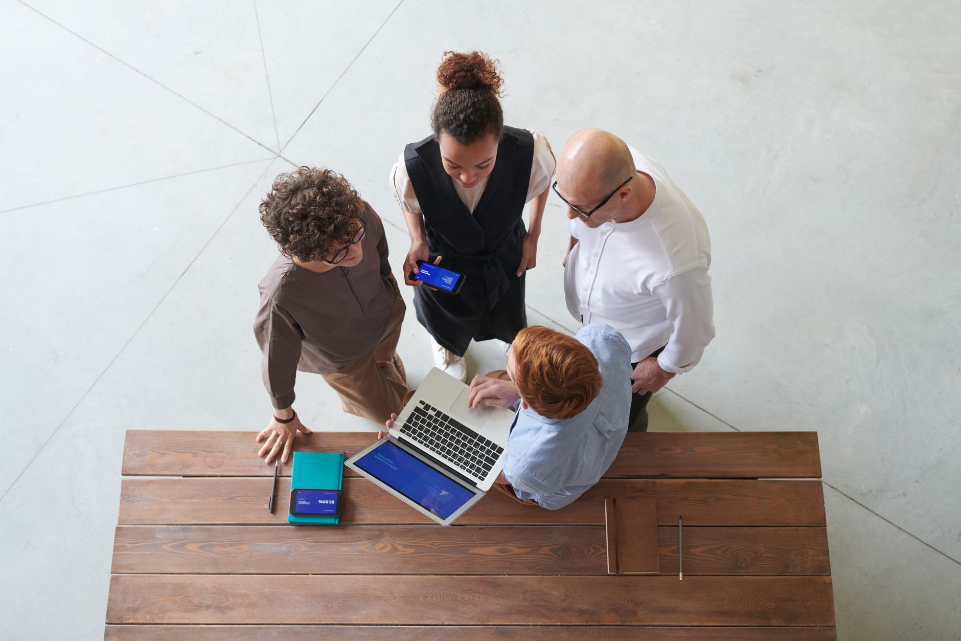 High angle view of colleagues discussing work around a laptop indoors, showcasing teamwork.