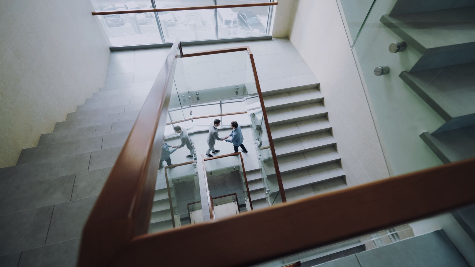 Aerial view of business professionals shaking hands on a modern staircase.