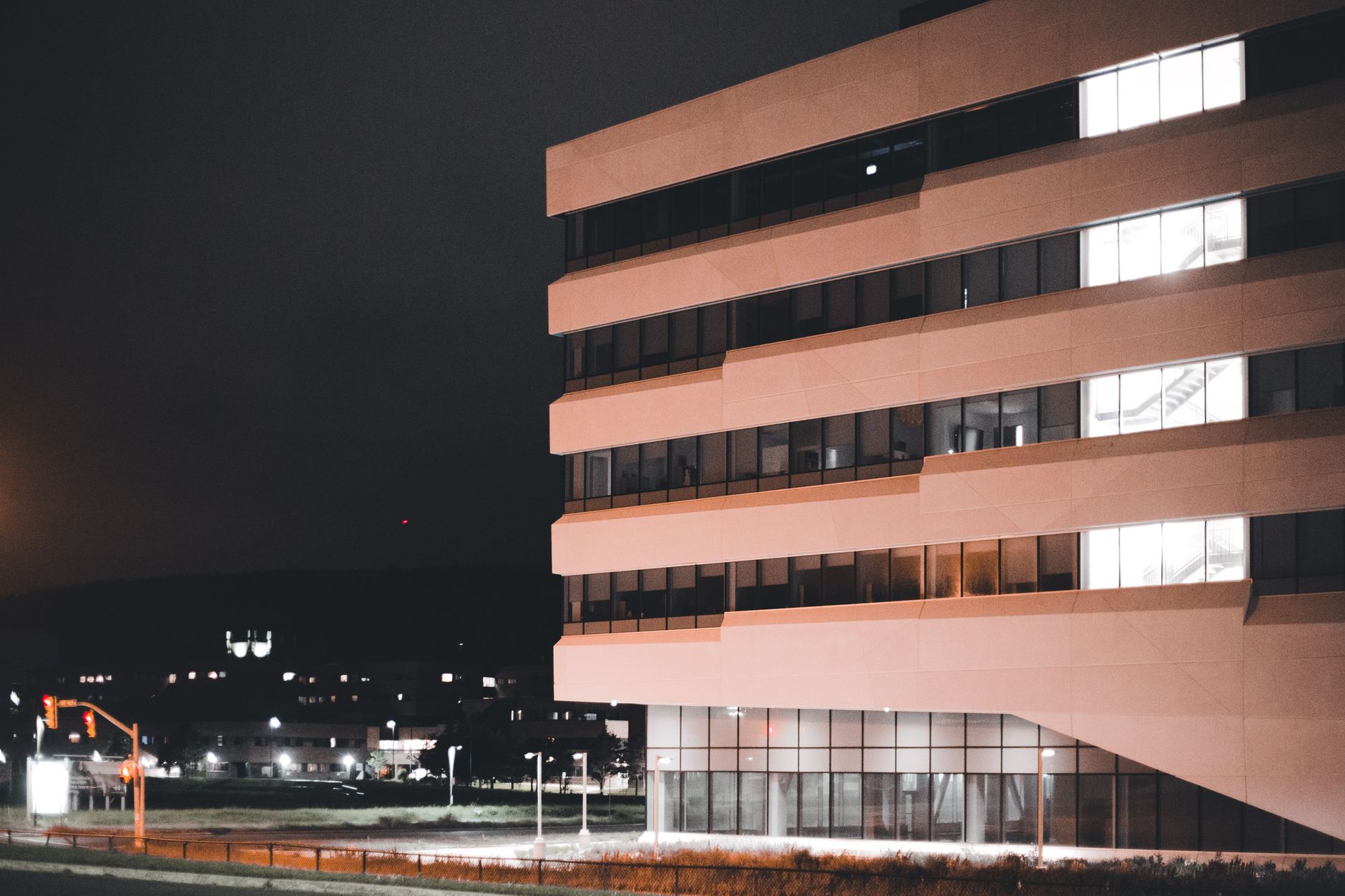 A contemporary office building with glowing windows set against a cityscape at night.