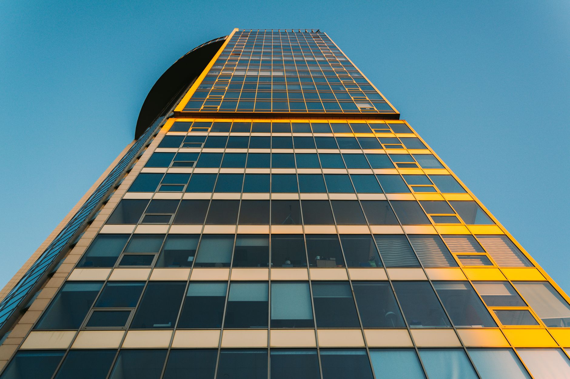 Low angle view of a glass skyscraper in St. Petersburg, highlighting modern architecture against a clear blue sky.
