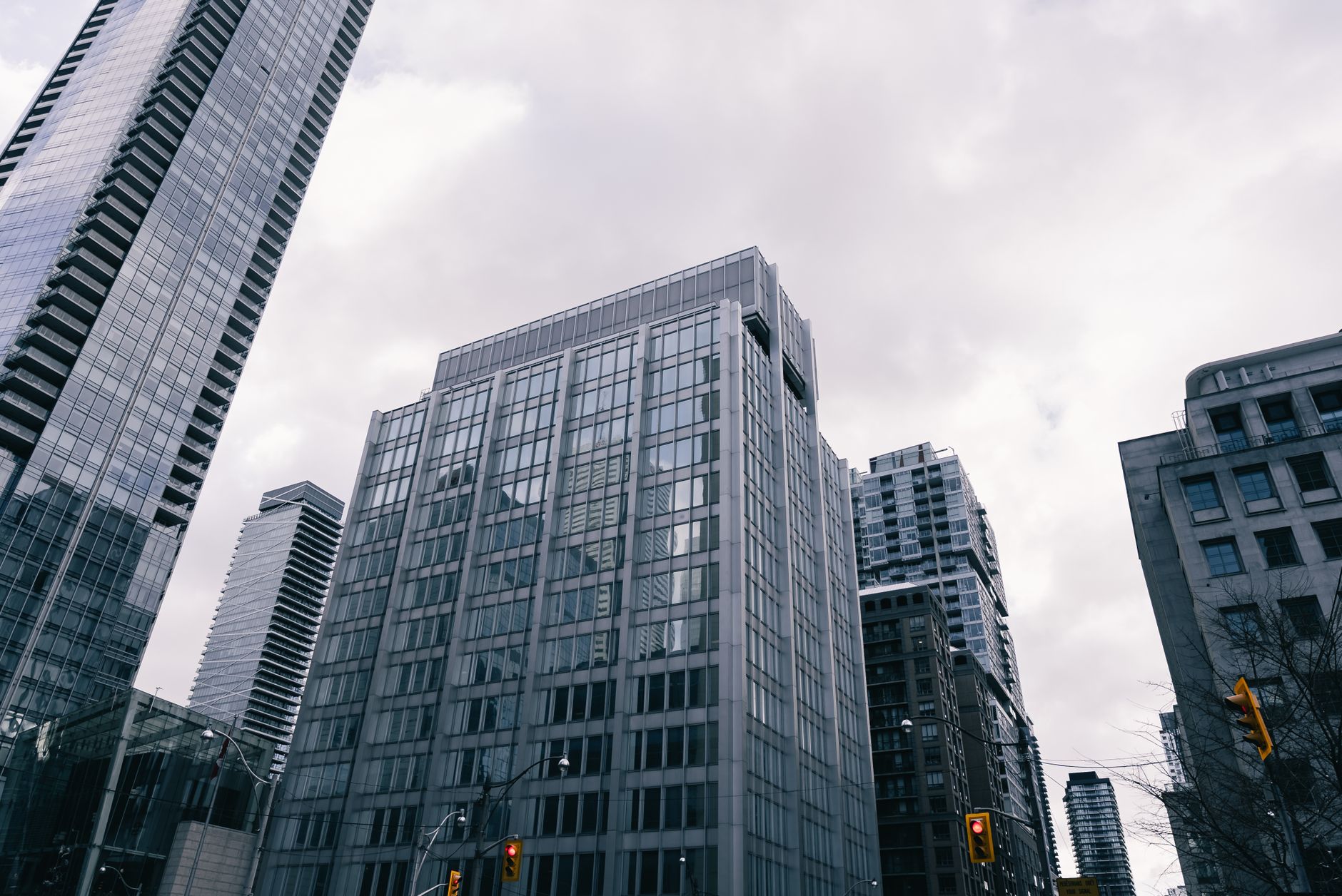 Low-angle view of modern skyscrapers under cloudy sky in an urban setting, showcasing city architecture.