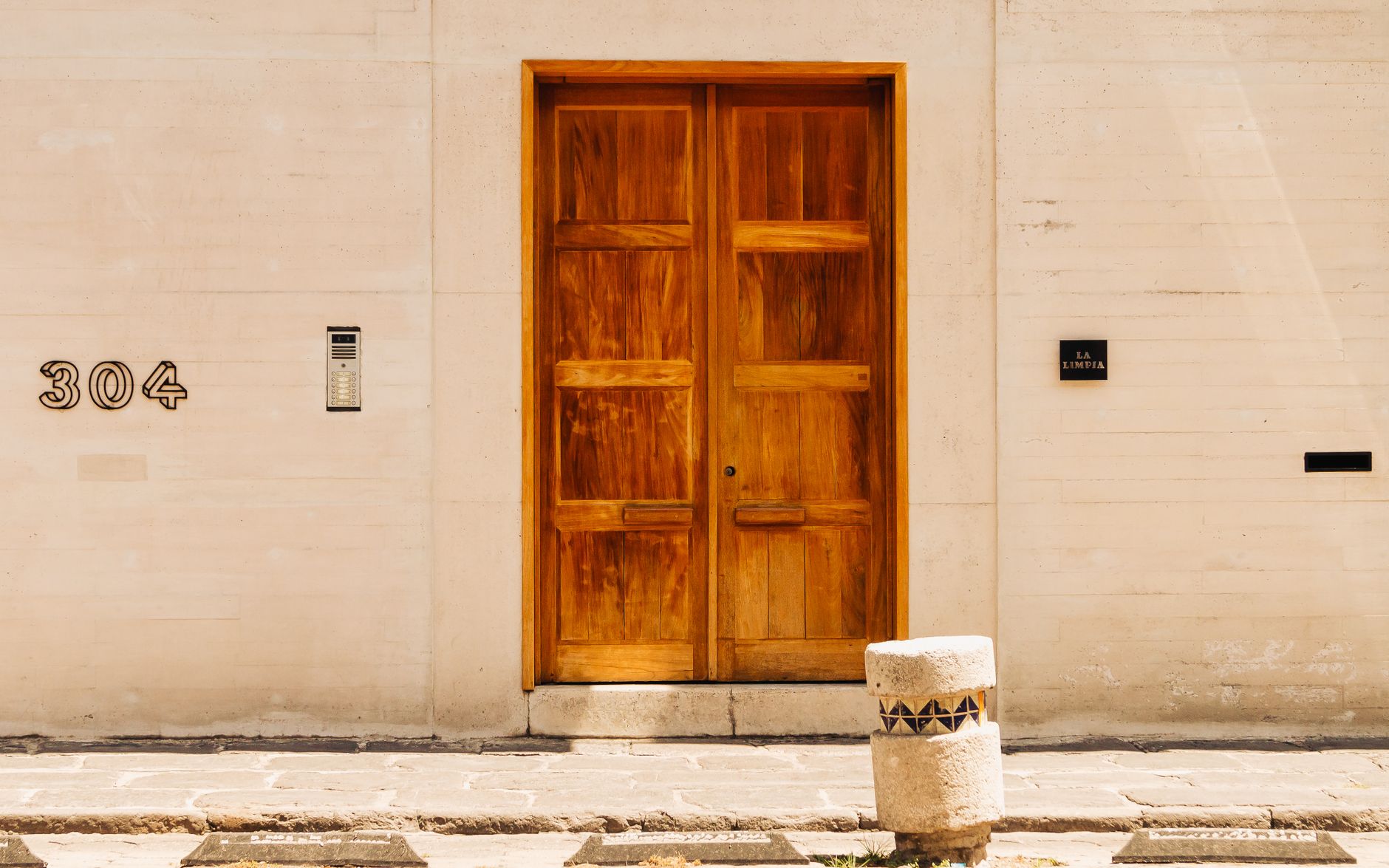 A stylish wooden door marked with 304, set against a minimalist wall, offering architectural elegance.