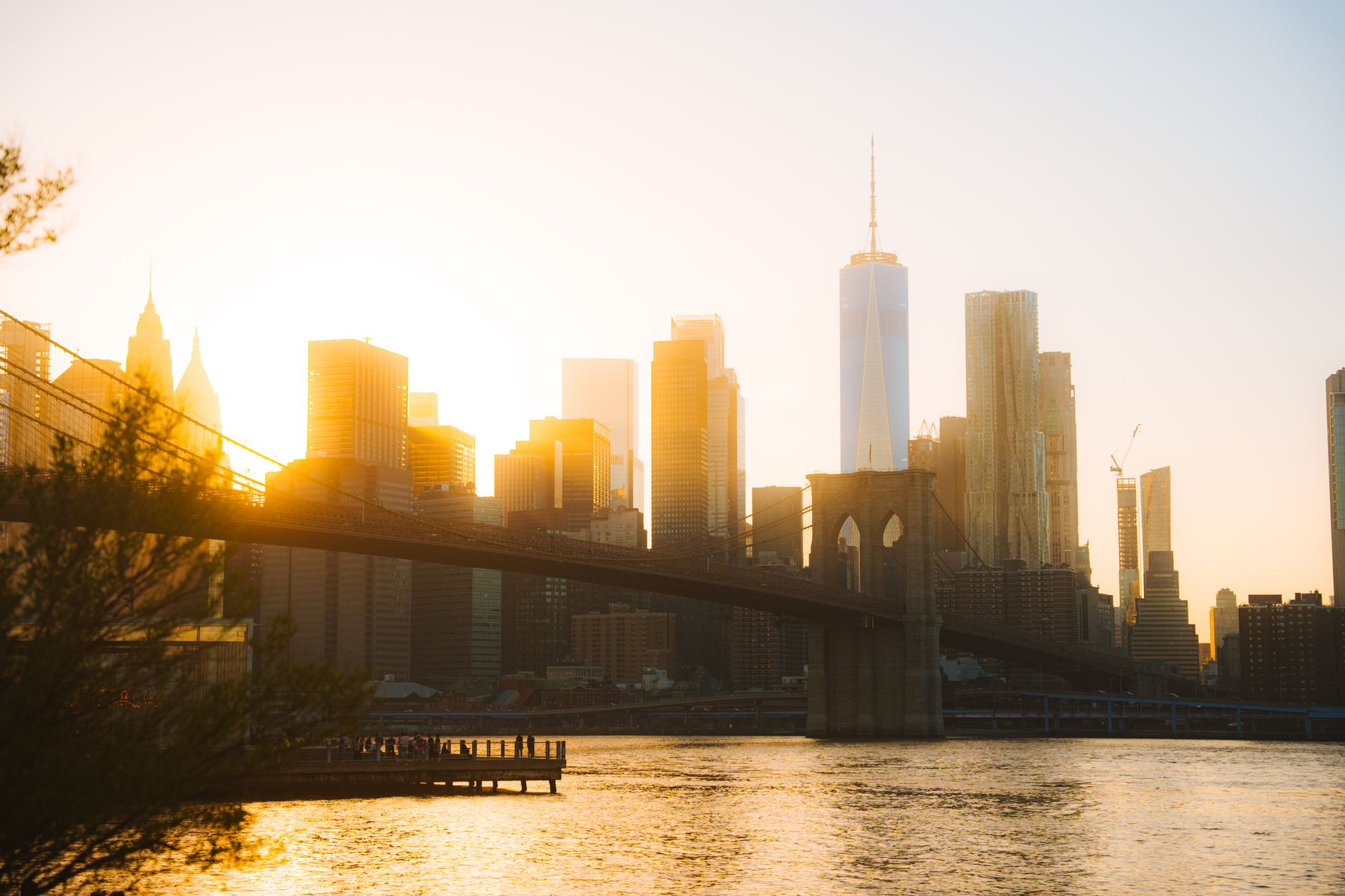 Captivating view of the Brooklyn Bridge against a golden New York City skyline at sunset.