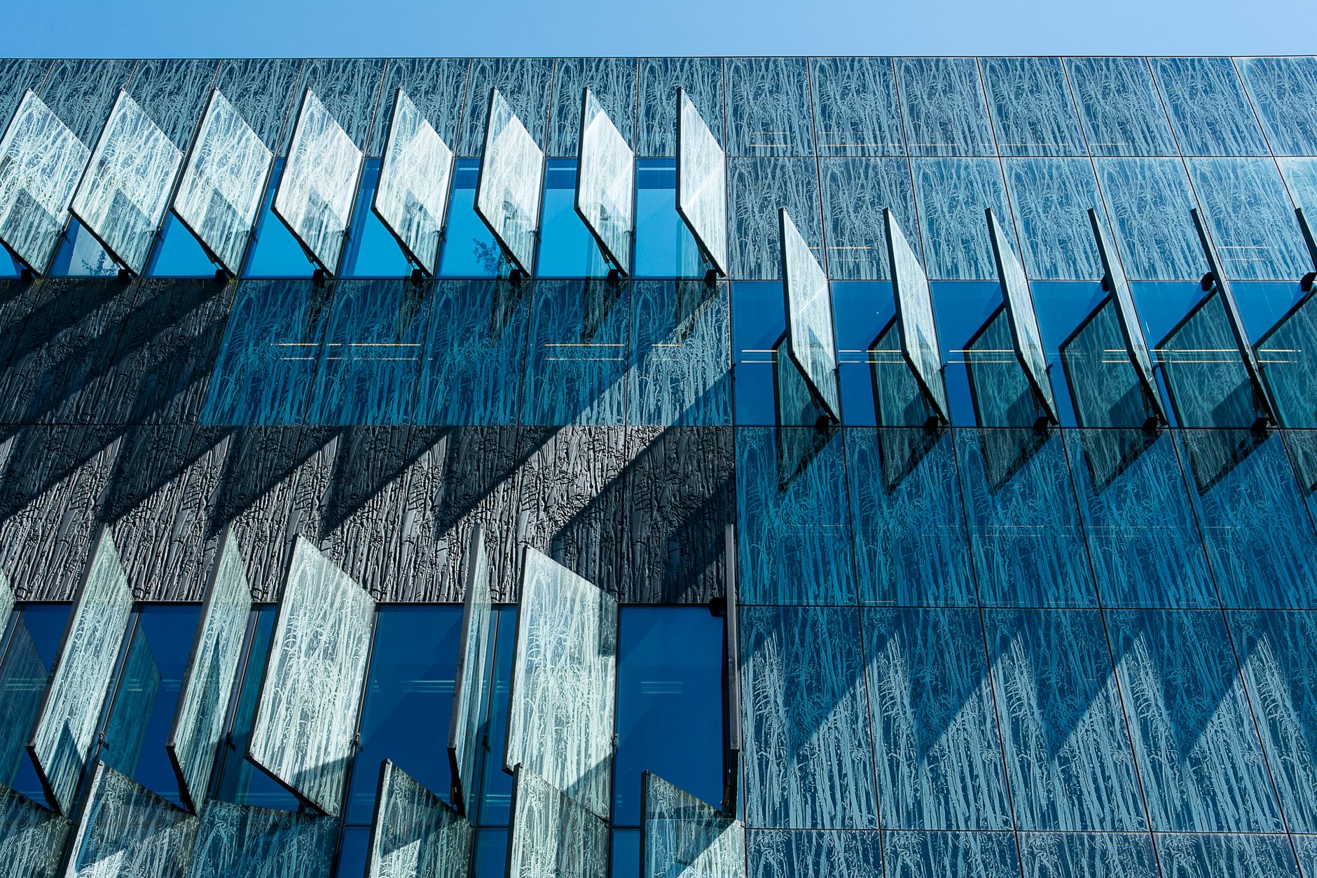 A contemporary building showcasing geometric patterns and glass panels in an urban environment.