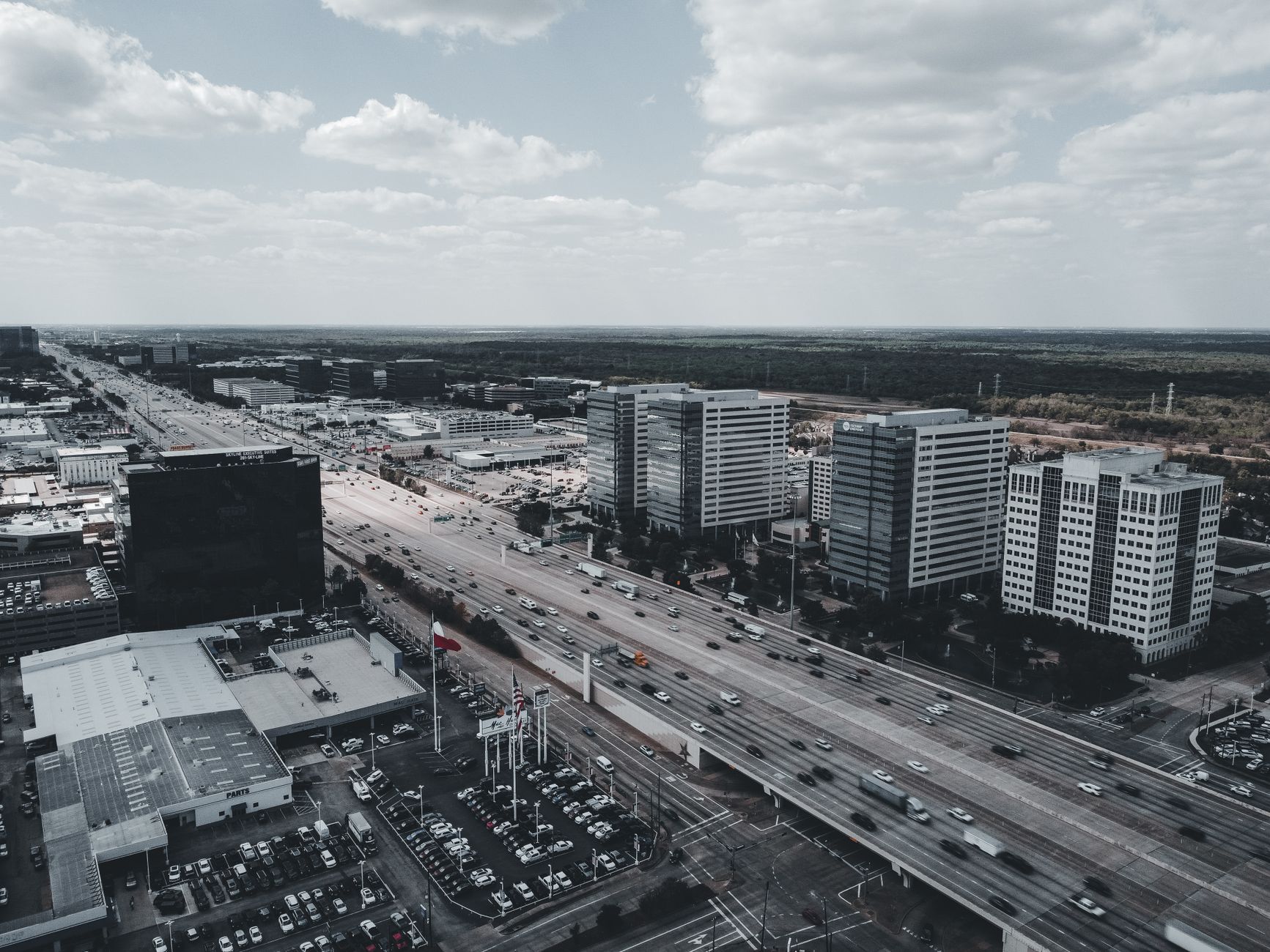 An aerial shot capturing a bustling highway intersecting a modern urban cityscape with tall buildings.