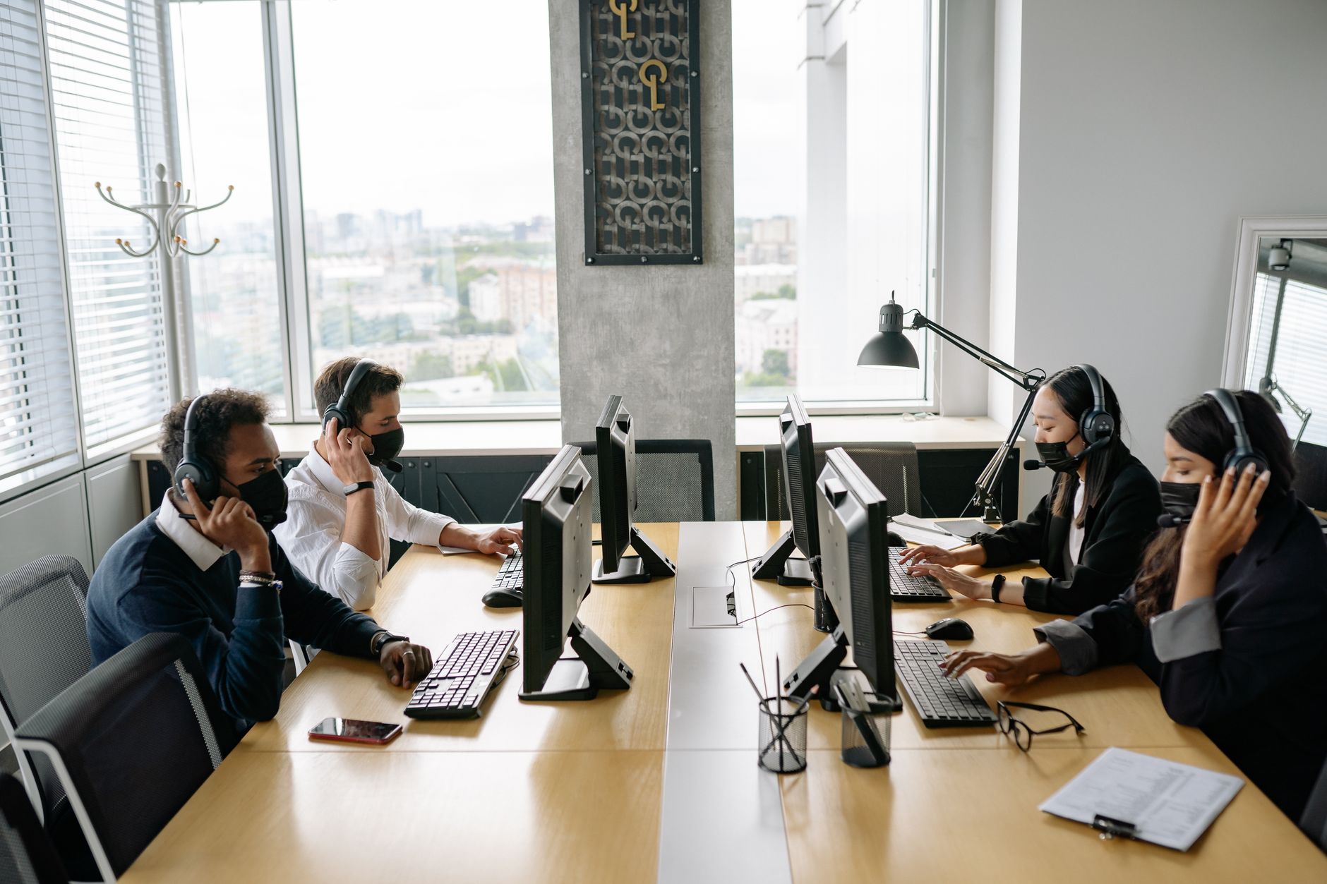 Professional team in a modern call center working collaboratively with headsets and computers.