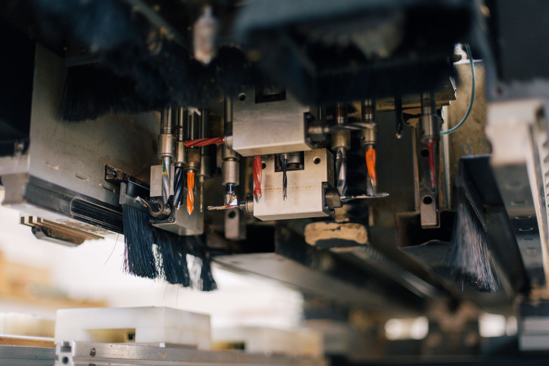 Detailed view of an industrial machine with multiple drills and brushes in a factory setting.
