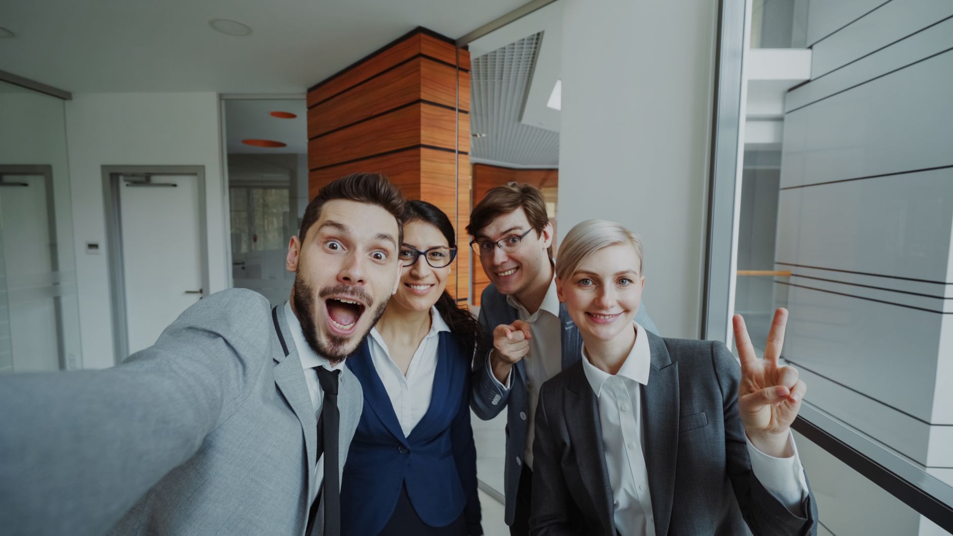 Diverse group of young professionals taking a cheerful office selfie.