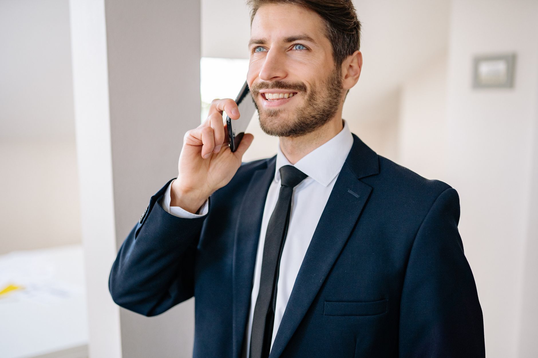 Confident businessman in suit making a phone call indoors, smiling.