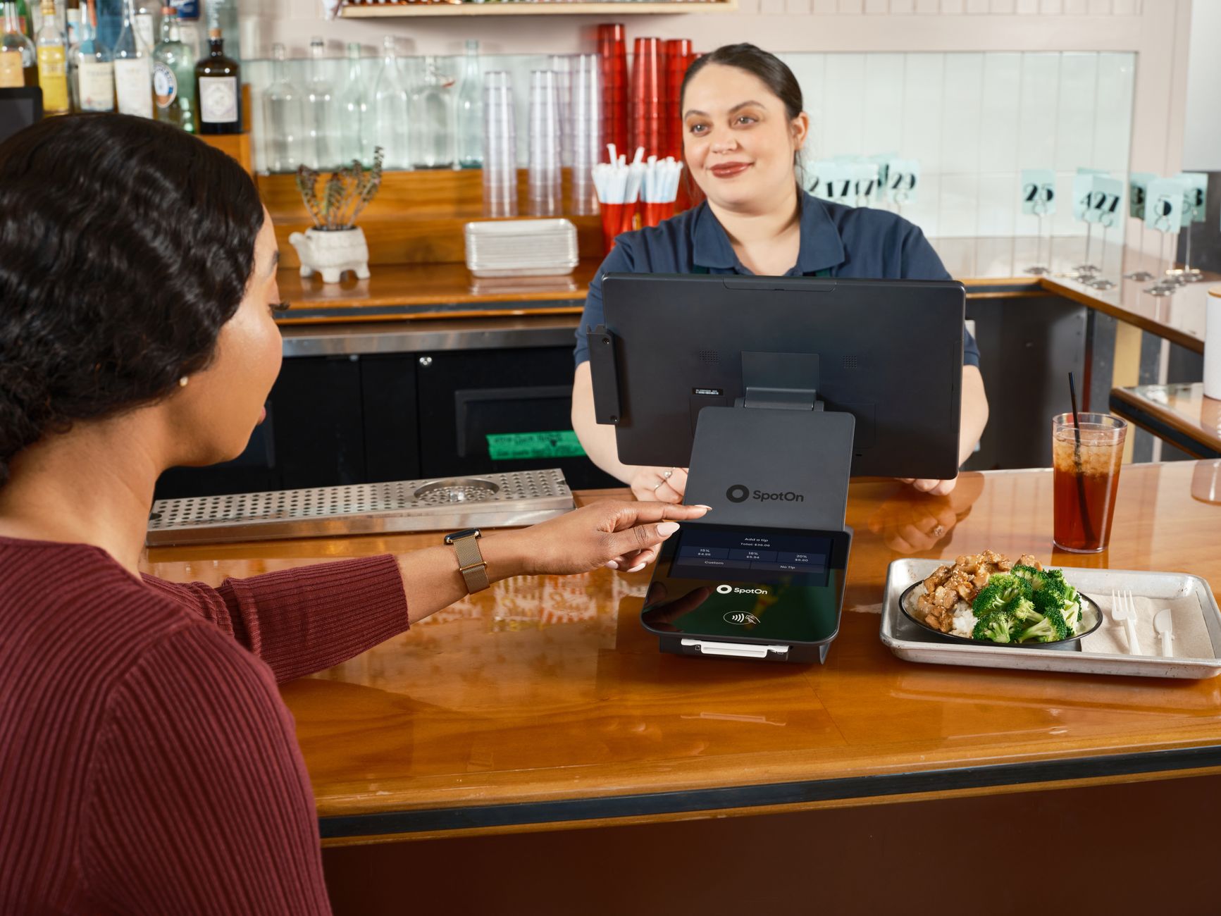 Woman using a digital tipping feature on a point of sale system in a restaurant setting.