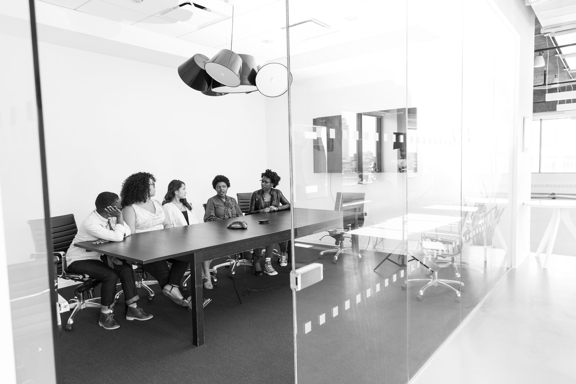 Group of professionals in a black and white office meeting discussing work around a conference table.