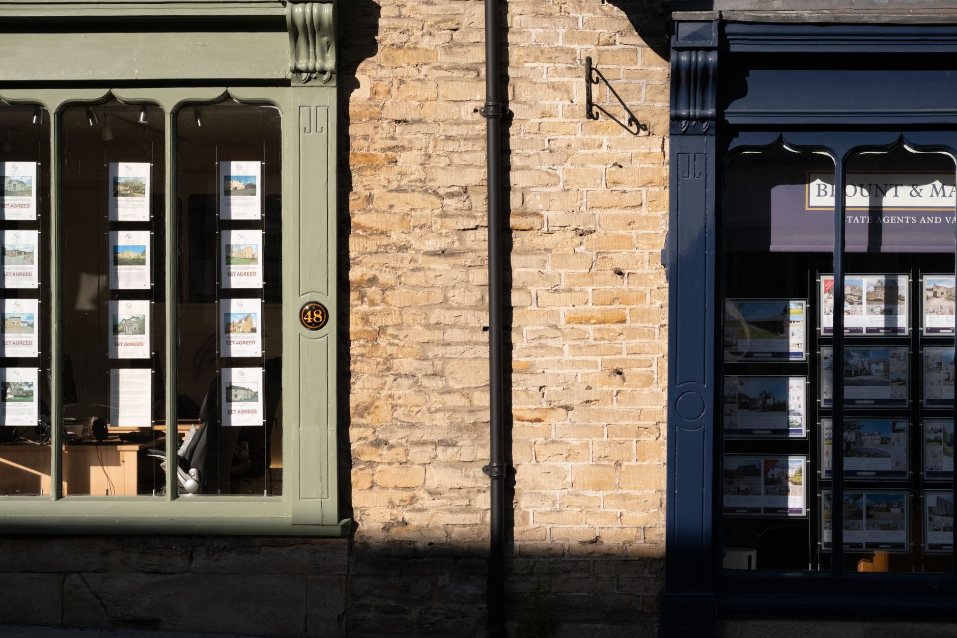 Sunlit display windows of an estate agency in Malmesbury, England.