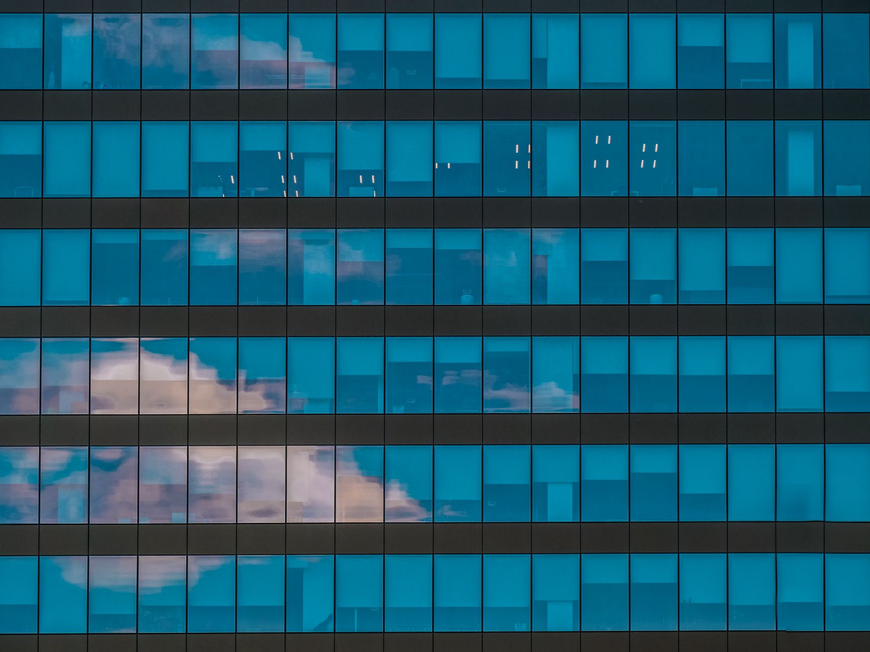 Reflection of clouds on a modern glass building facade in Timișoara, Romania.