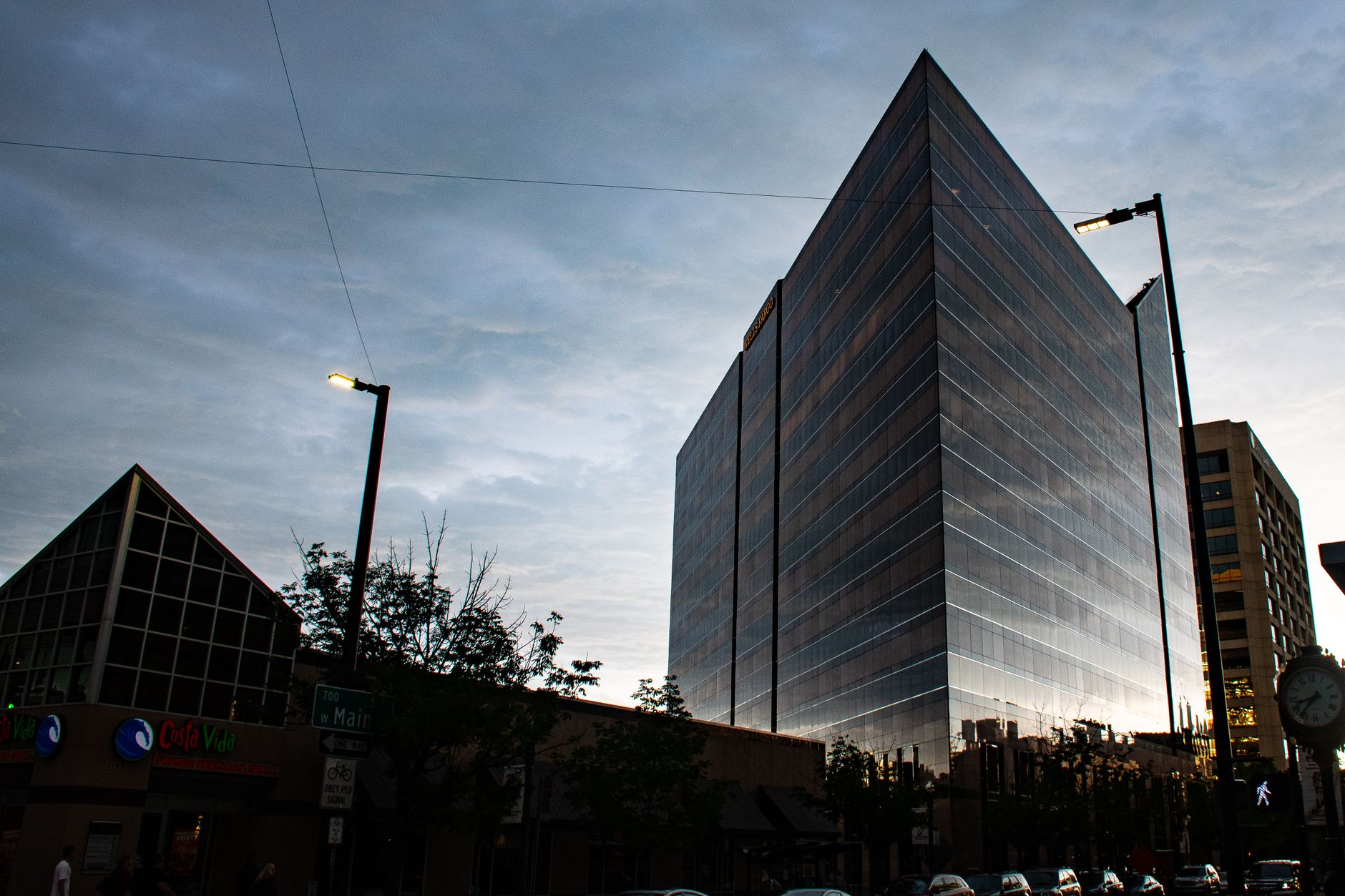 Capture of a sleek, modern skyscraper against a twilight sky in a bustling urban setting.