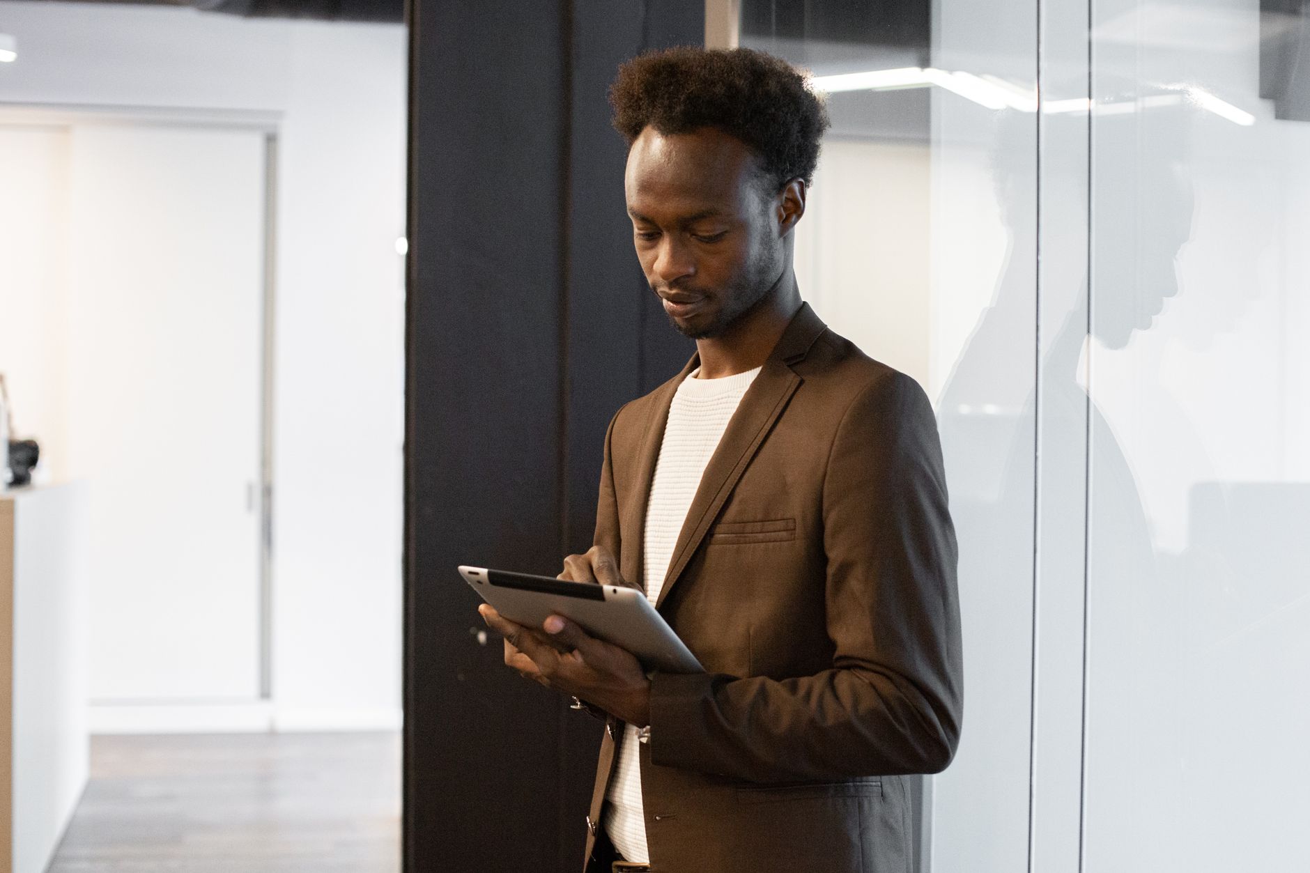 A professional man in business attire using a tablet in a modern office setting.