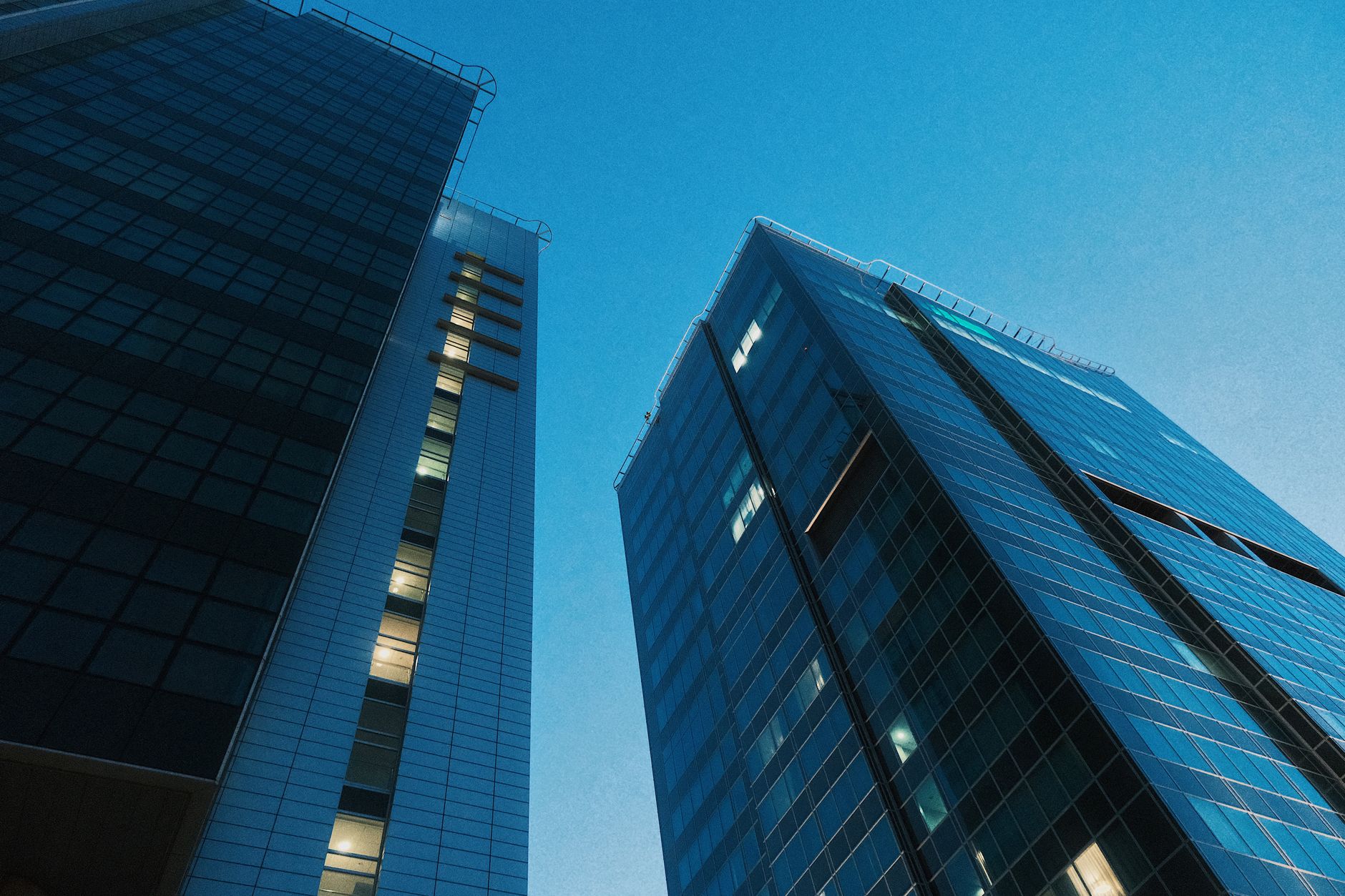 Low angle view of modern skyscrapers with glass facades against a clear evening sky in Poznań, Poland.