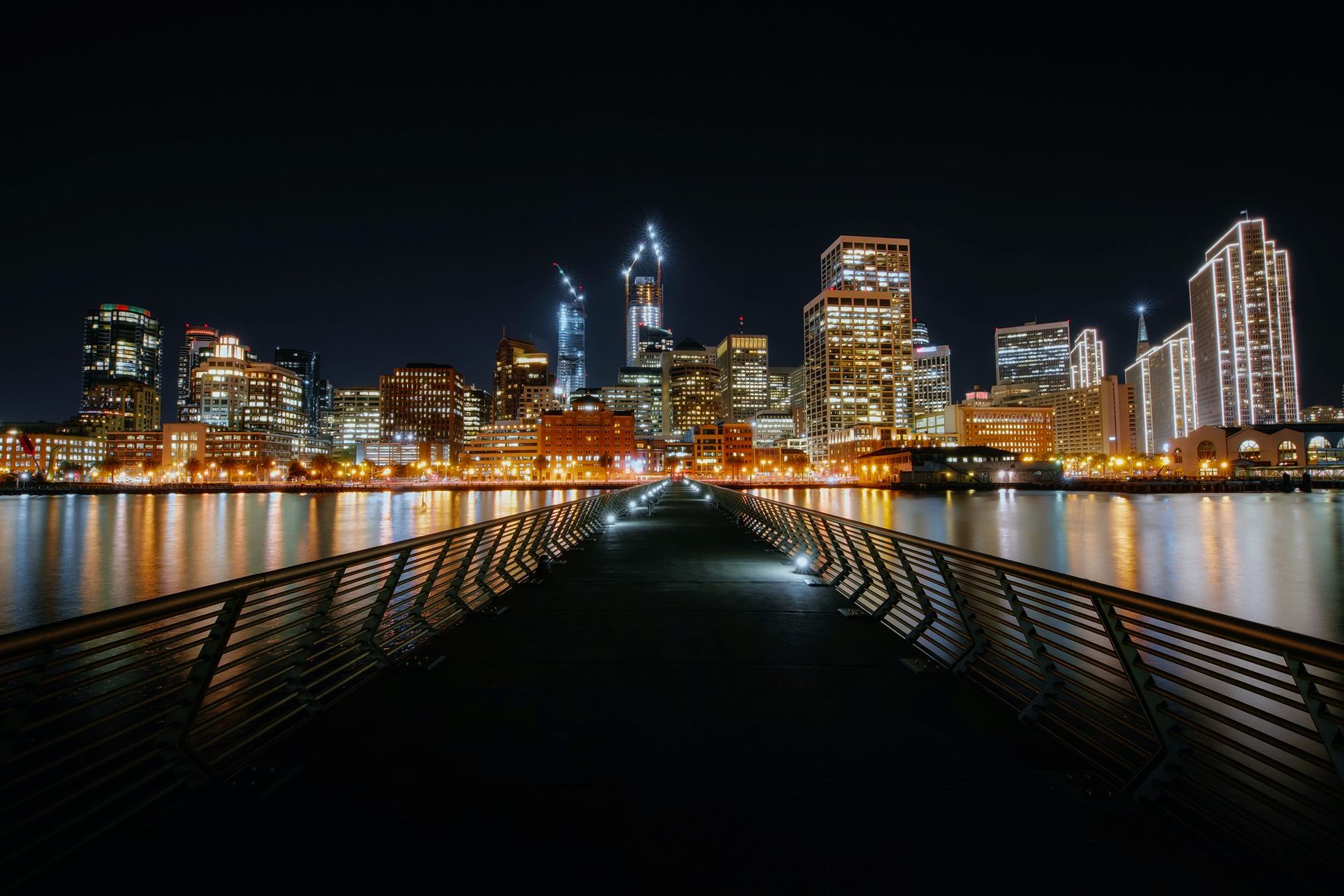Dazzling San Francisco skyline at night with glowing city lights reflecting on water.