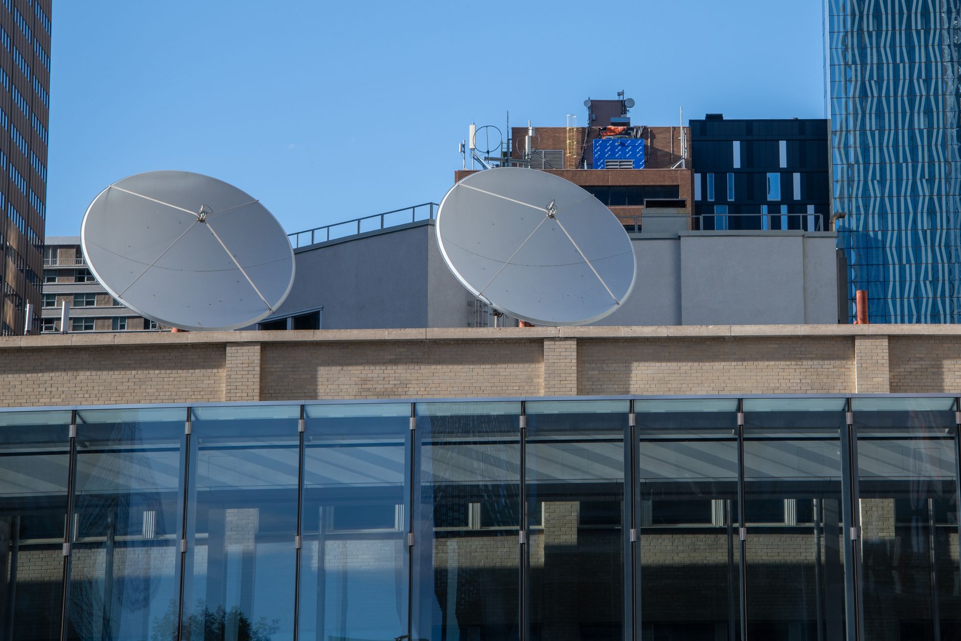 Urban rooftop view featuring satellite dishes against Calgary's modern architecture.