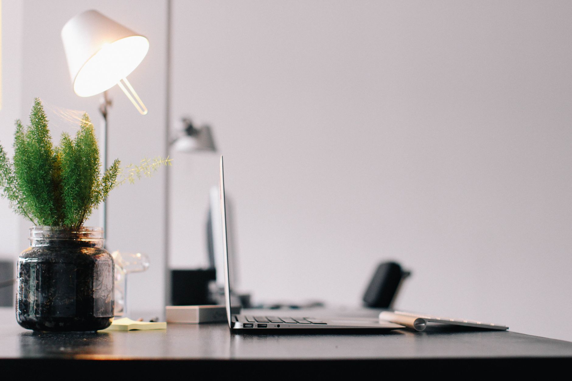 Stylish modern office desk with laptop, lamp, and indoor plant for productive work environment.
