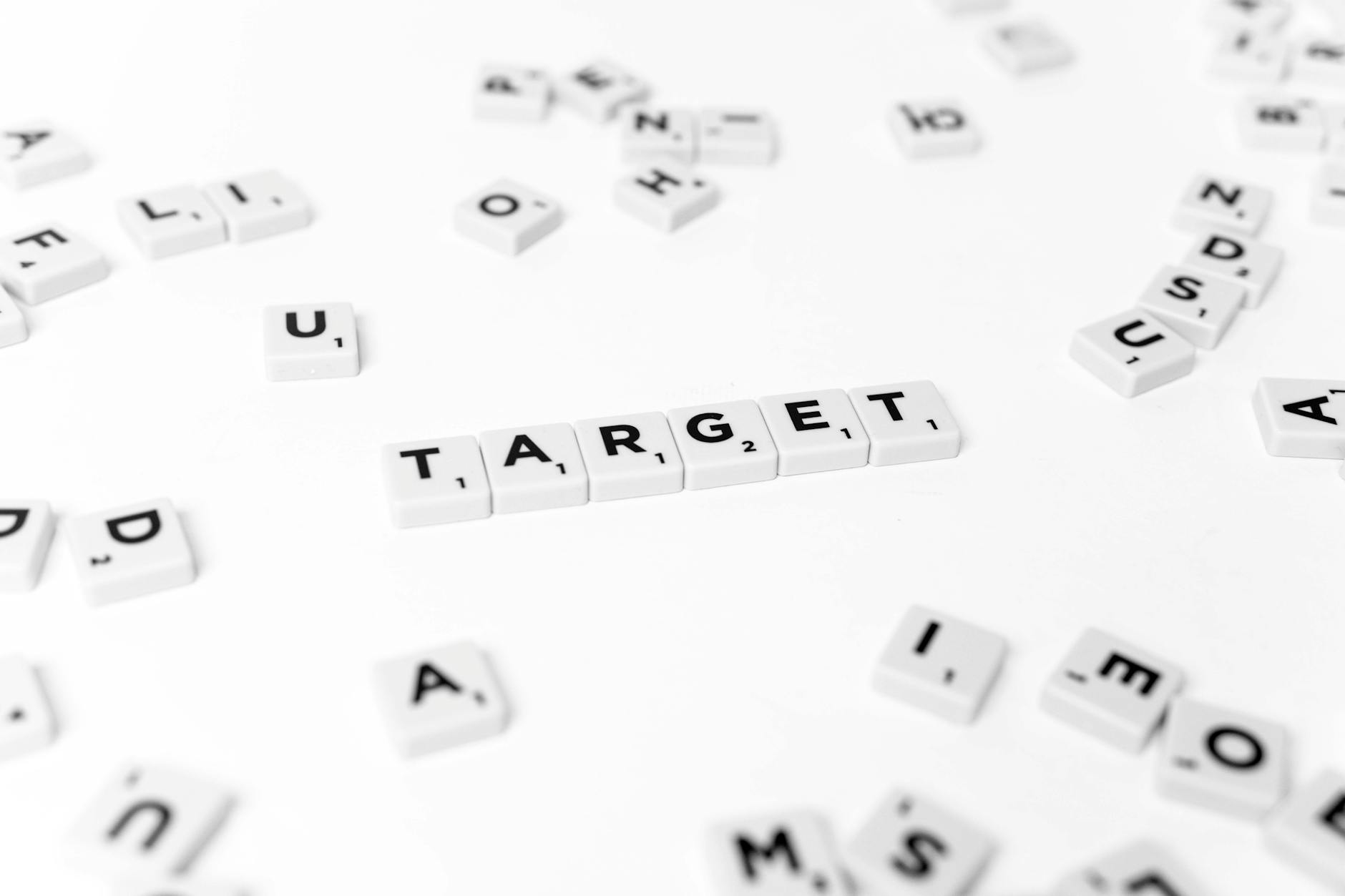 Close-up of "TARGET" spelled with Scrabble tiles on a white background. Conceptual and selective focus.
