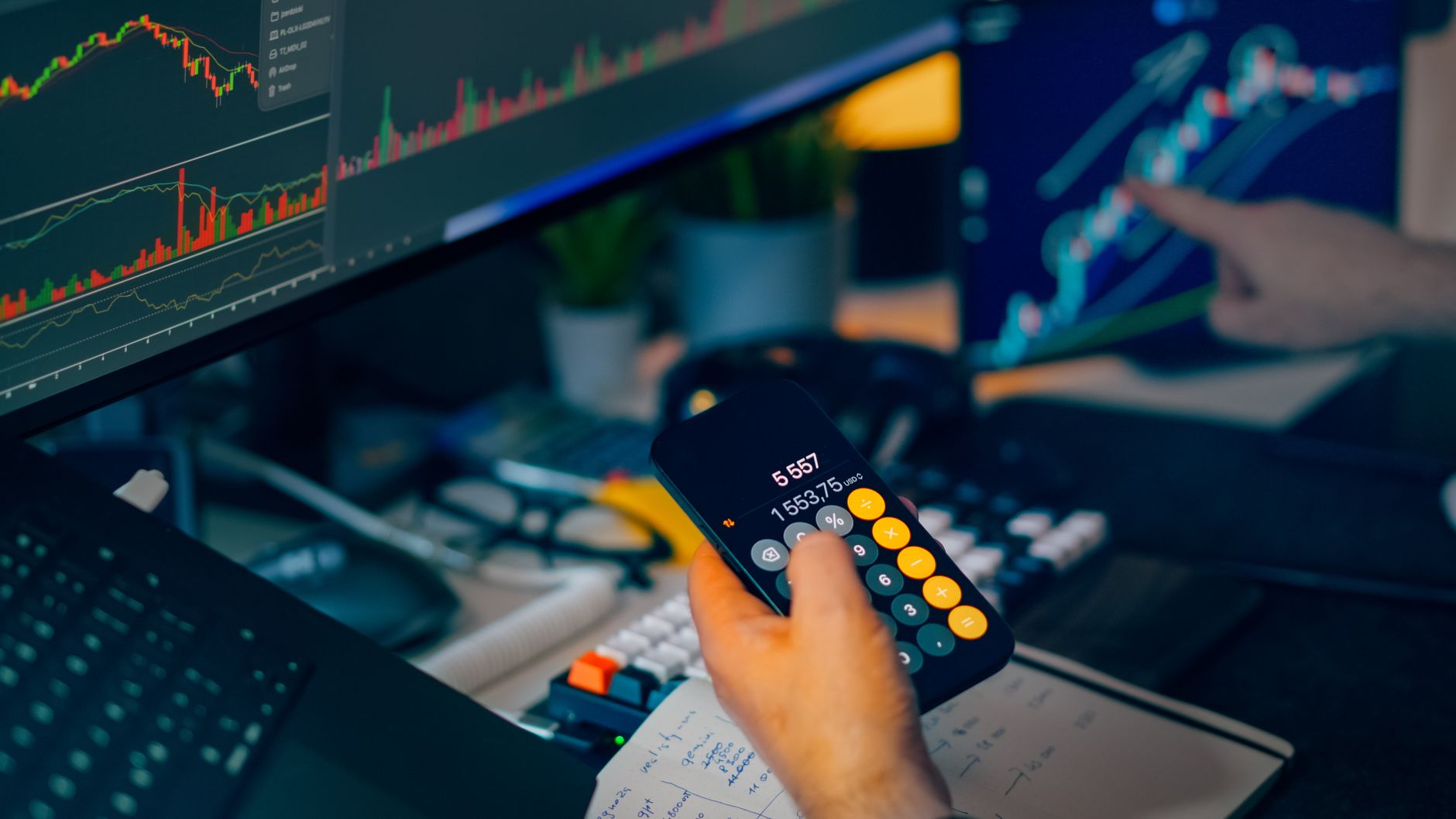 A focused shot of financial trading with screens, calculator, and data charts.