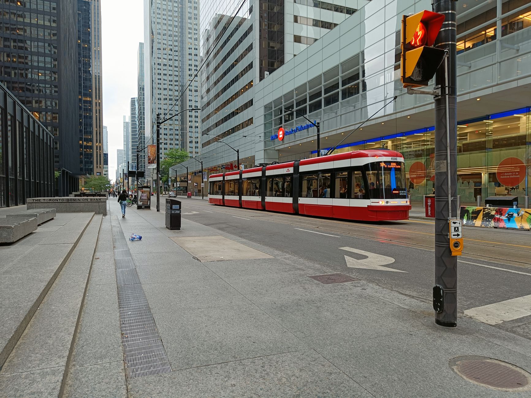 A modern streetcar travels through a bustling downtown Toronto street.